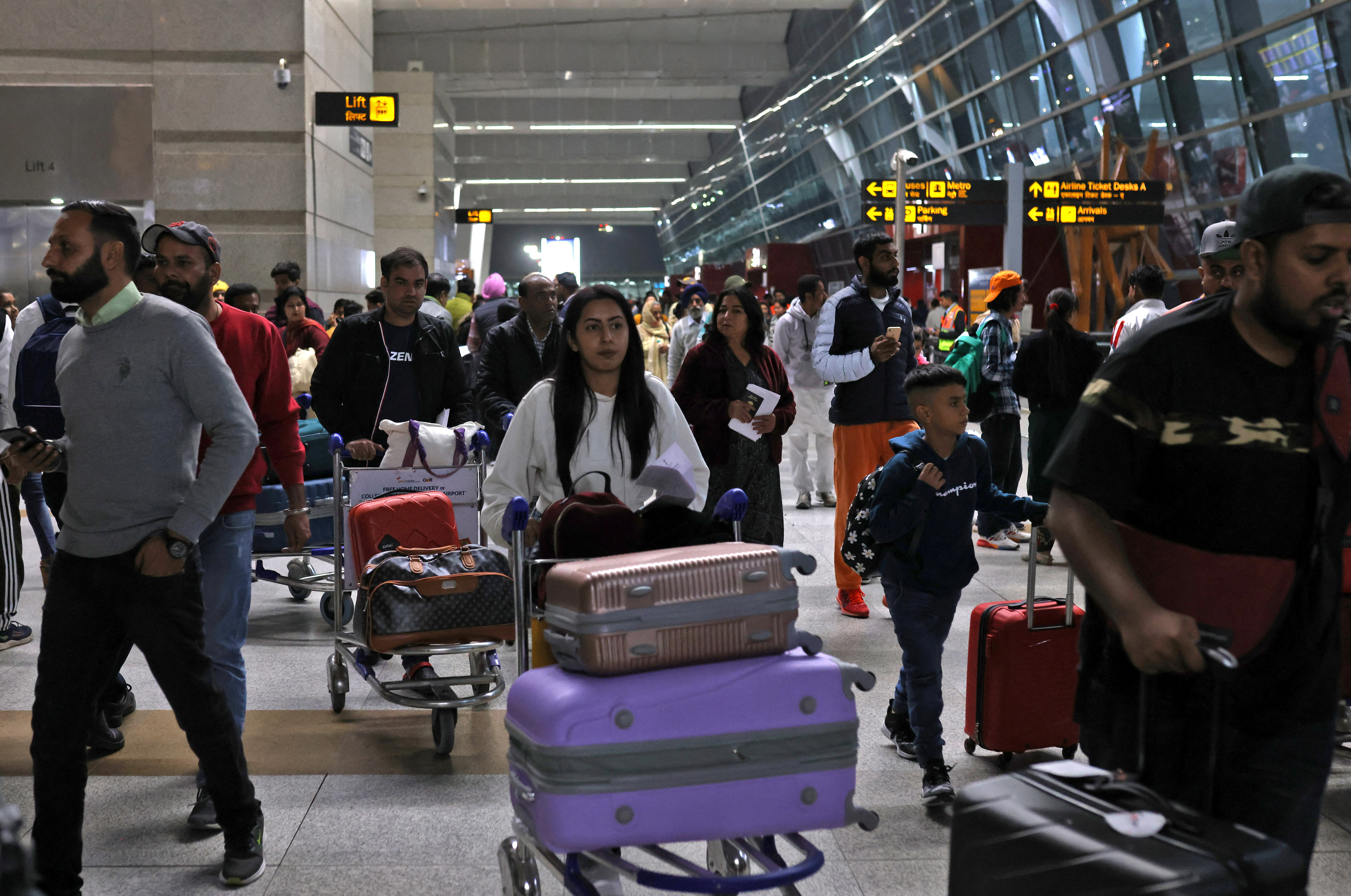 Travellers push carts with their luggage at the departure area of Terminal 3 at Indira Gandhi International Airport in New Delhi