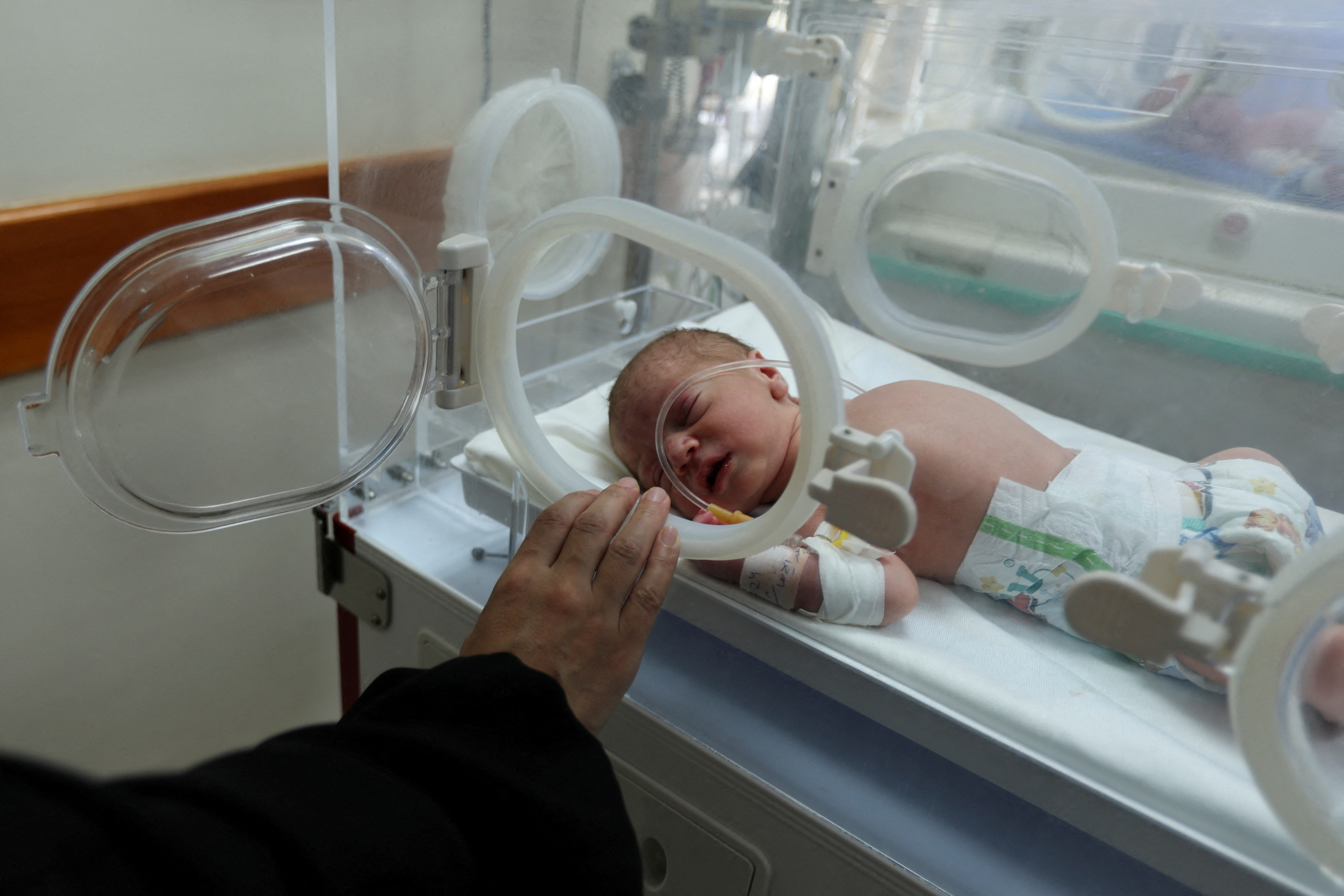 Palestinian baby Malek Yassin, who was saved from the womb of his mother Ola Al-Kurd, who was killed in an Israeli strike, according to medics, lies in an incubator at a hospital in central Gaza Strip