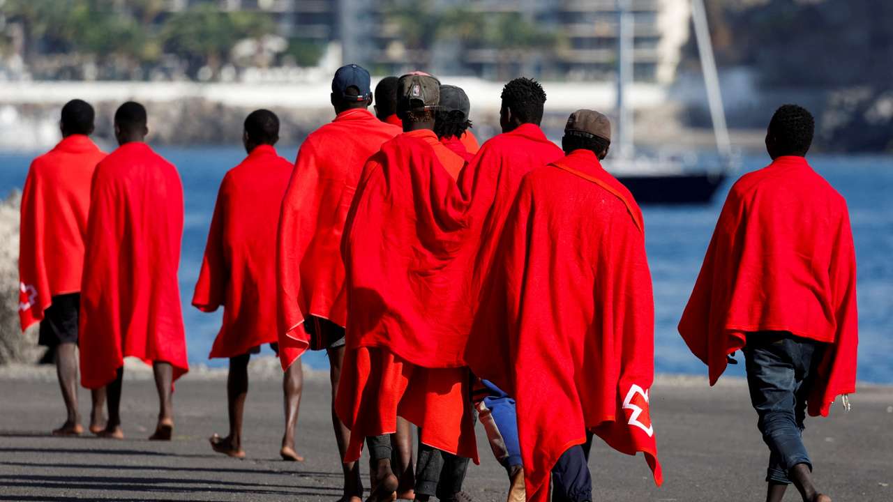 FILE PHOTO: A group of migrants walk in the port of Arguineguin to be assisted by the Red Cross after disembarking from a Spanish coast guard vessel