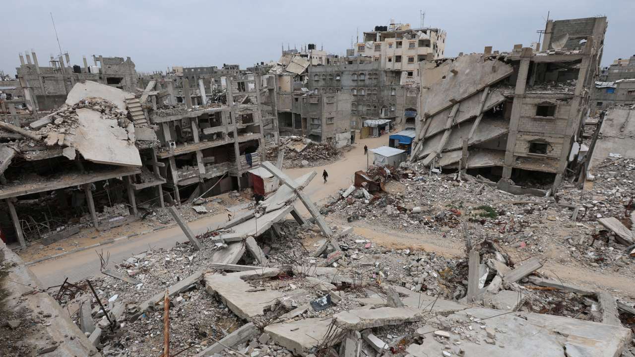 FILE PHOTO: Palestinians walk surrounded by the rubble of houses destroyed in Israeli strikes during the war, in Khan Younis