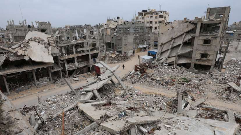 FILE PHOTO: Palestinians walk surrounded by the rubble of houses destroyed in Israeli strikes during the war, in Khan Younis