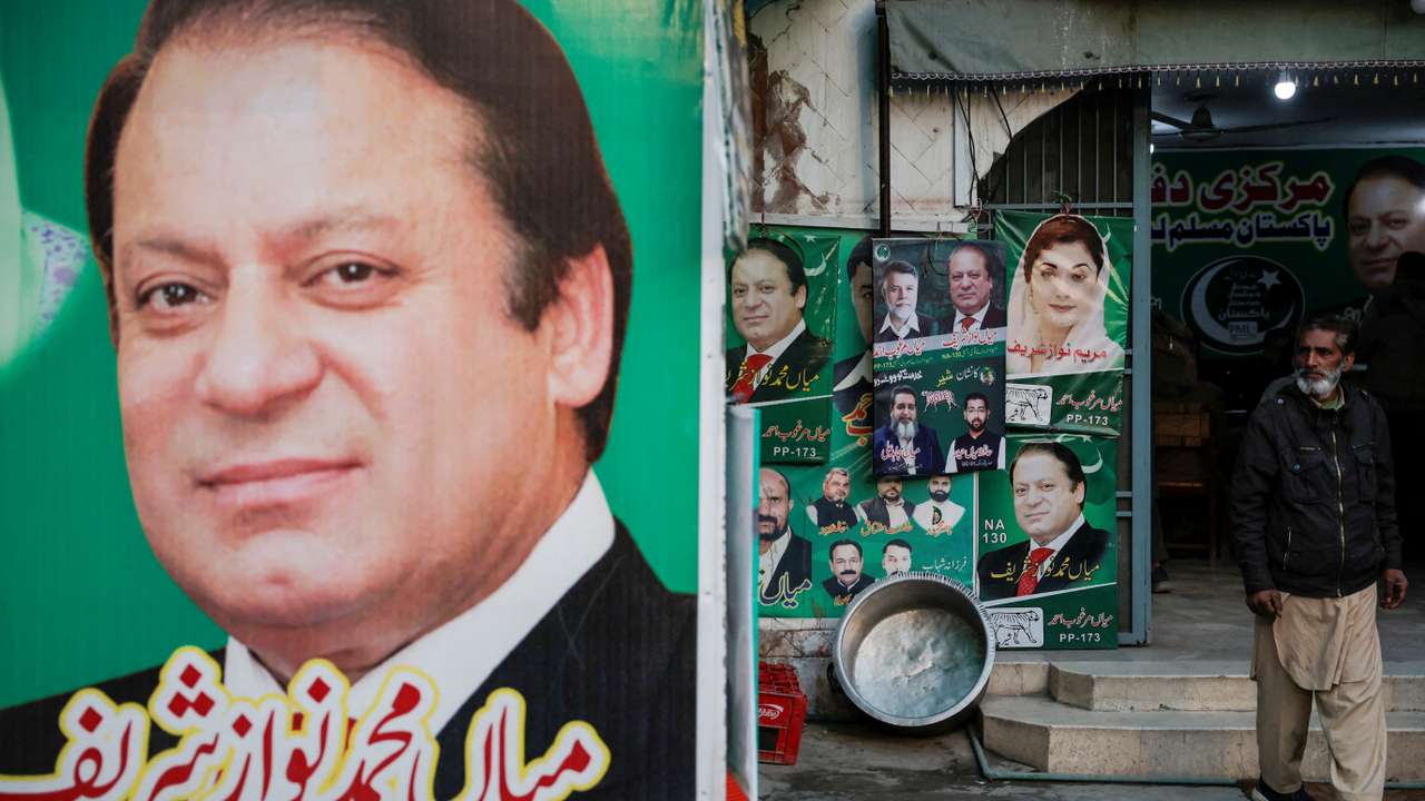 FILE PHOTO: A man stands near the banner and campaign posters of Pakistan's former Prime Minister Nawaz Sharif ahead of the general elections