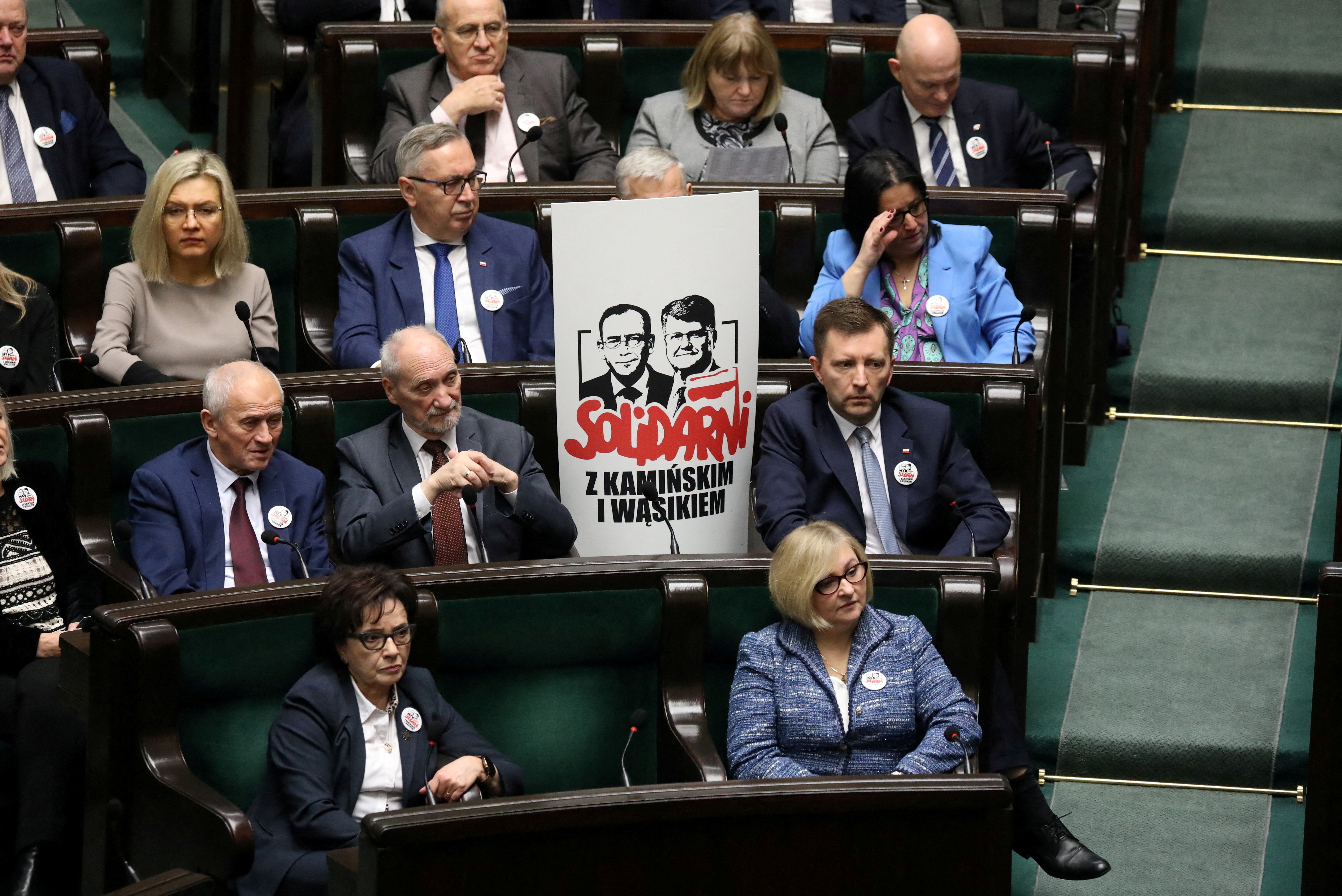 FILE PHOTO: Polish members of parliament from PiS party sit next to poster with images of former Interior Minister Kaminski and his deputy Wasik during parliamentary session in Warsaw