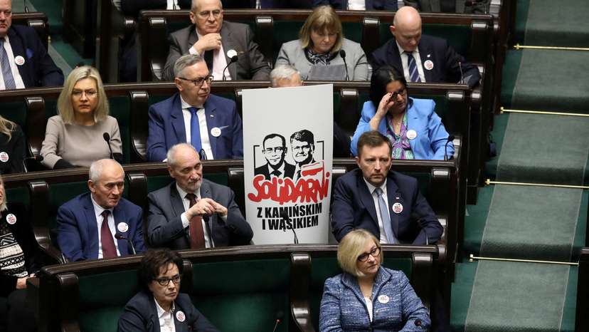 FILE PHOTO: Polish members of parliament from PiS party sit next to poster with images of former Interior Minister Kaminski and his deputy Wasik during parliamentary session in Warsaw