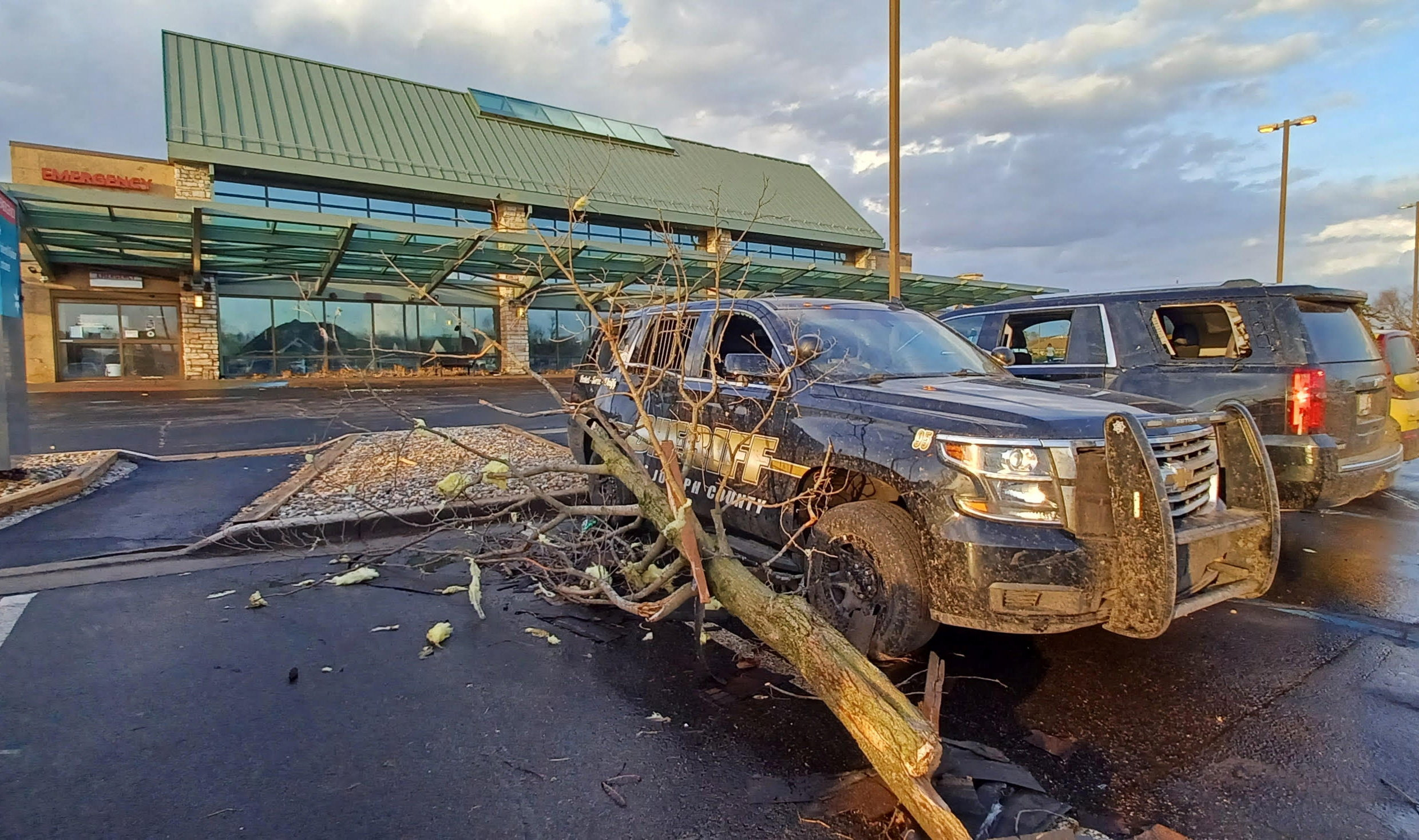 A fallen tree rests again a Sheriff's vehicle outside a hospital following storms and tornado warnings in Three Rivers