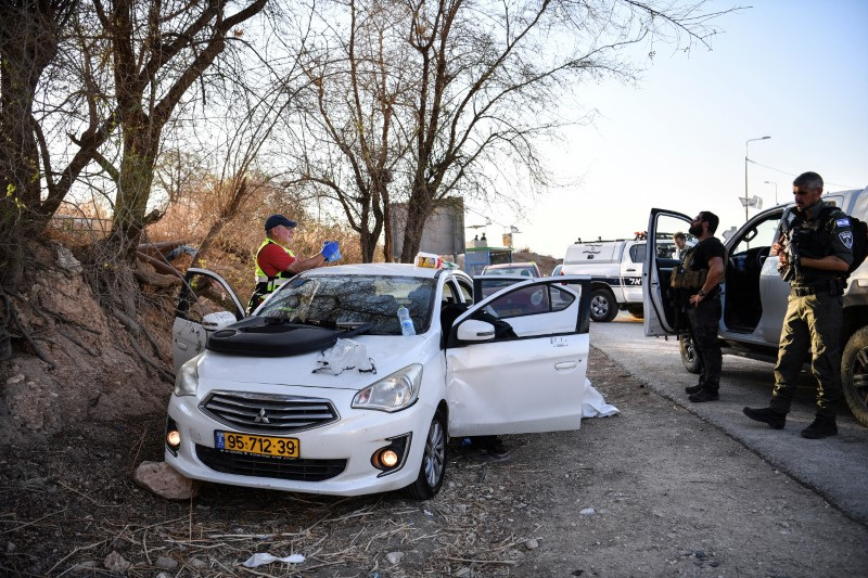 Israeli emergency services and soldiers stands next to a car with bullet holes at the scene of a suspected shooting attack near Mehola junction in the Jordan Valley, in the Israeli-occupied West Bank