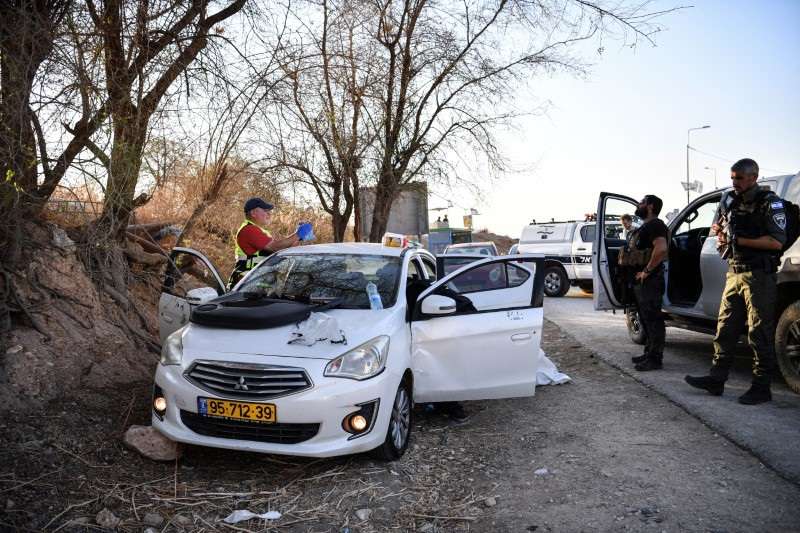 Israeli emergency services and soldiers stands next to a car with bullet holes at the scene of a suspected shooting attack near Mehola junction in the Jordan Valley, in the Israeli-occupied West Bank