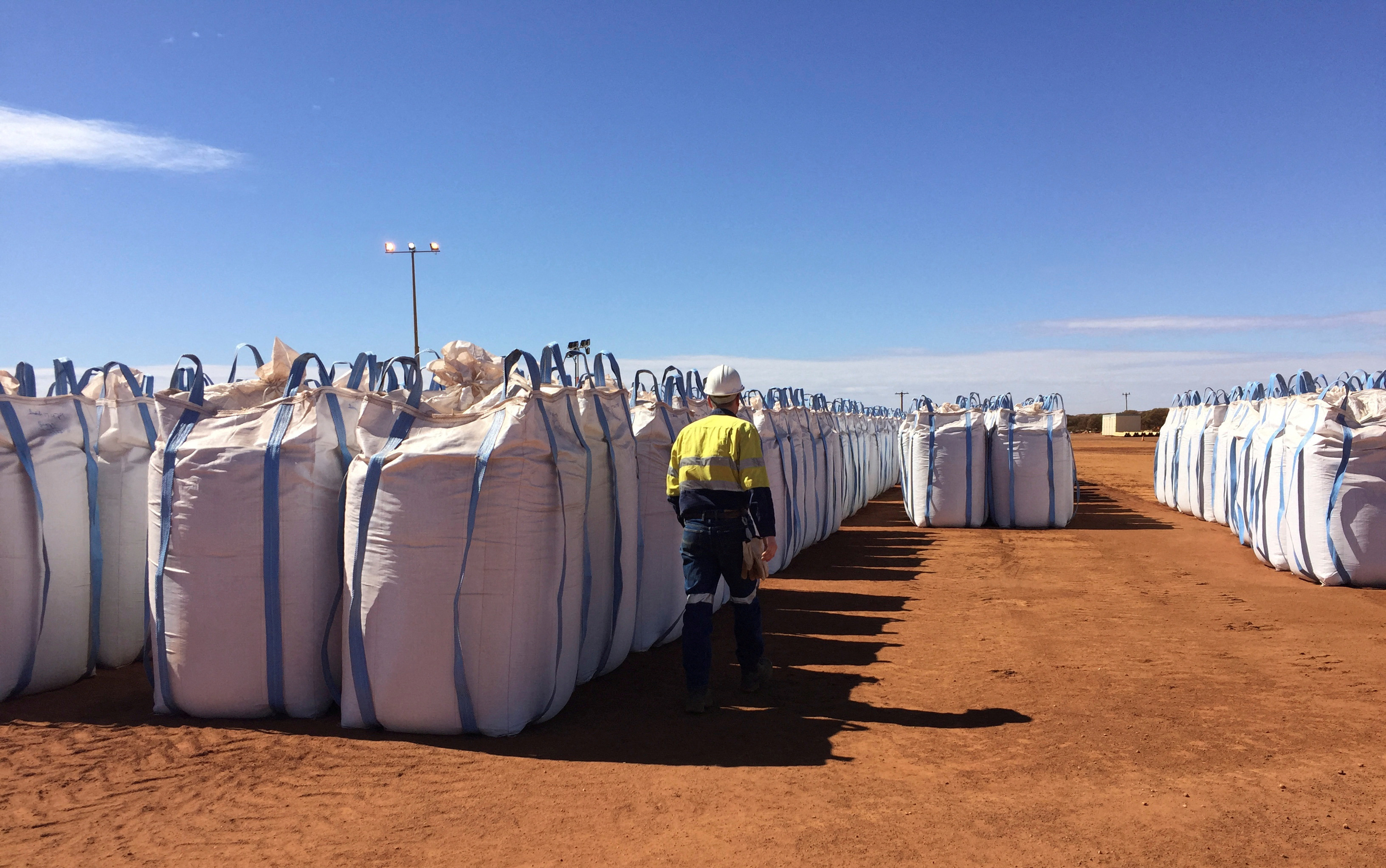 FILE PHOTO: A Lynas Corp worker walks past sacks of rare earths concentrate waiting to be shipped to Malaysia, at Mount Weld, northeast of Perth, Australia