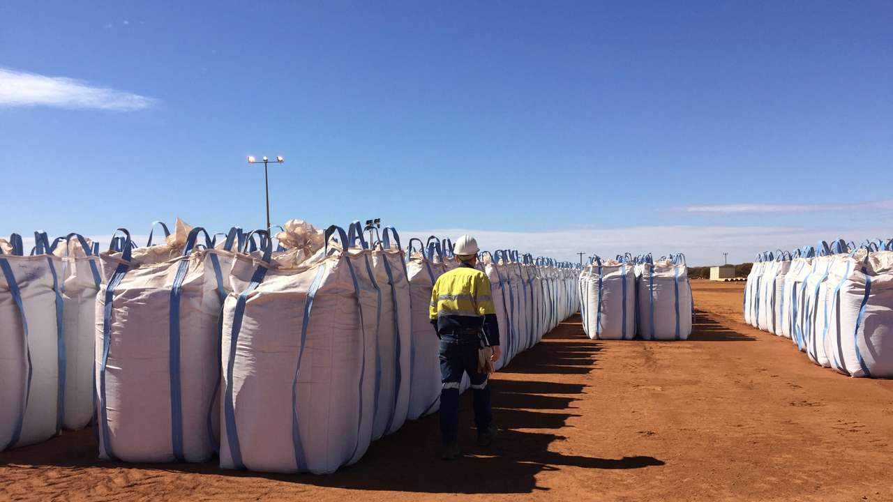 FILE PHOTO: A Lynas Corp worker walks past sacks of rare earths concentrate waiting to be shipped to Malaysia, at Mount Weld, northeast of Perth, Australia