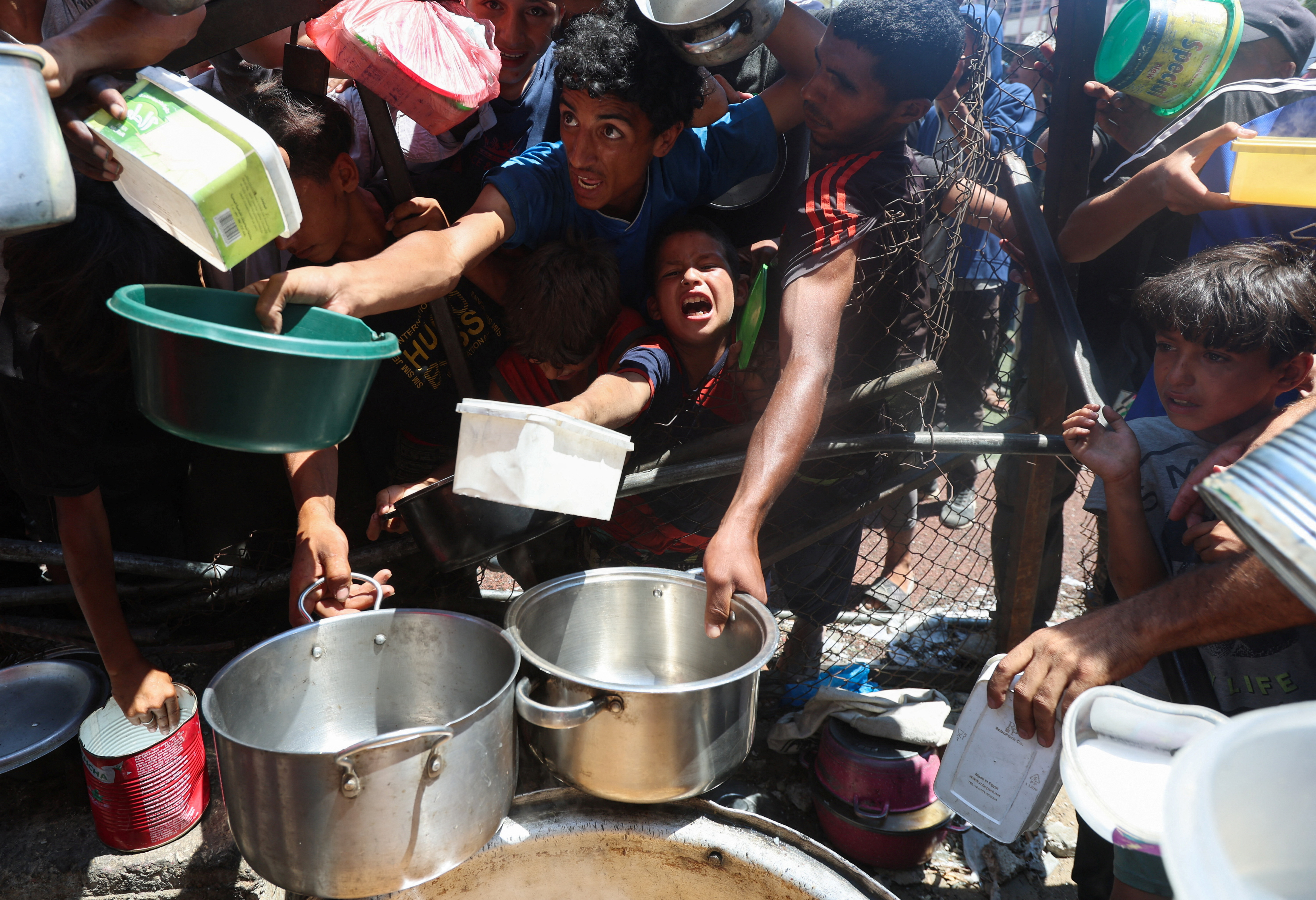 Palestinians gather to receive food from a charity kitchen, amid a hunger crisis, in Nuseirat