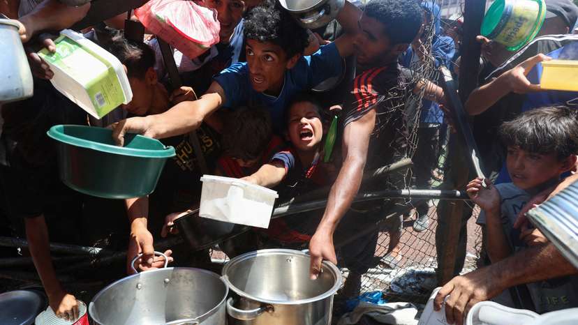 Palestinians gather to receive food from a charity kitchen, amid a hunger crisis, in Nuseirat
