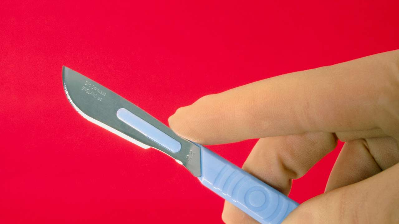 Gloved hand holding a disposable medical scalpel