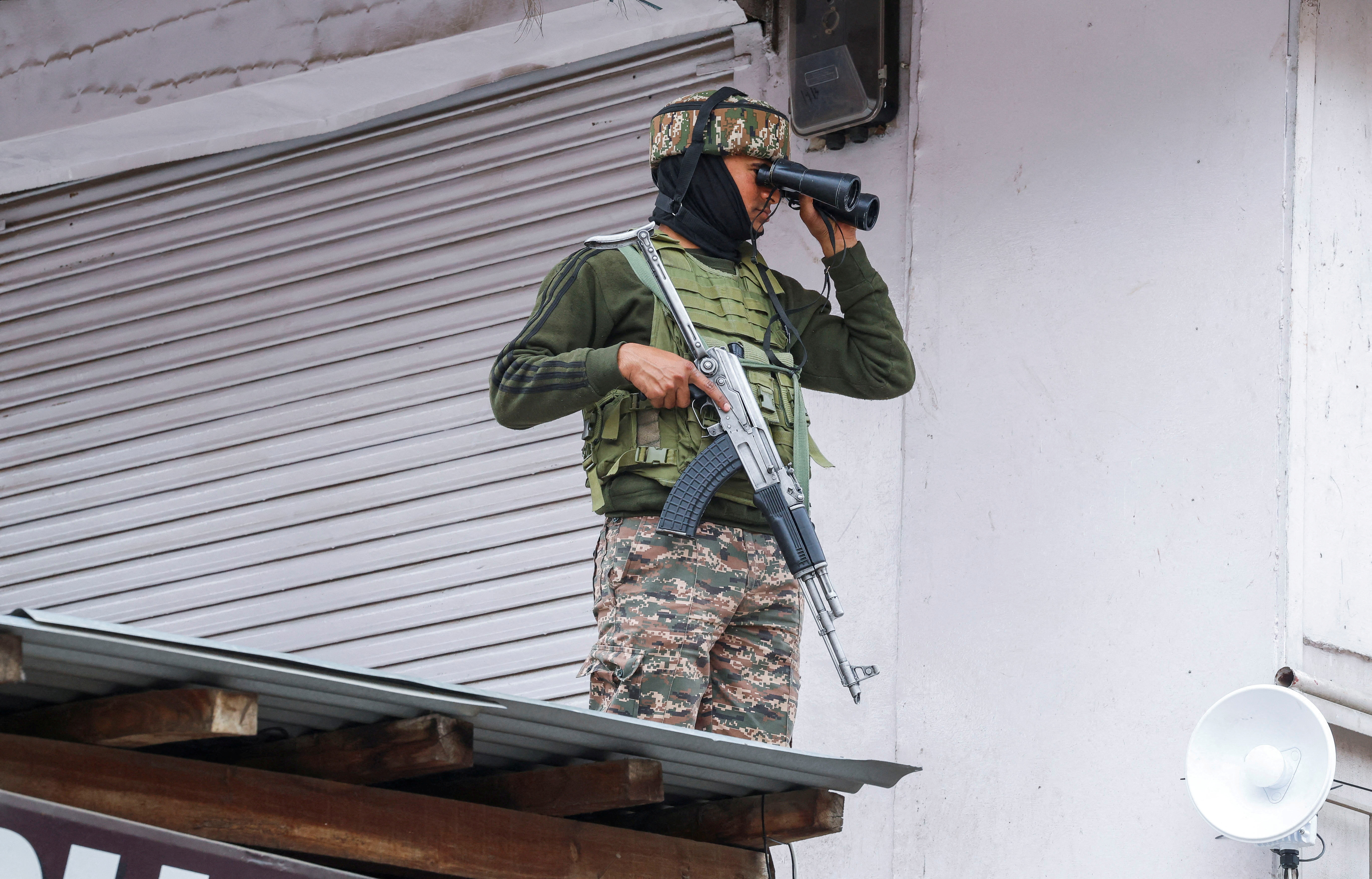 An Indian security force personnel uses binoculars as he stands on a rooftop, following the Pahalgam attack in south Kashmir, in Srinagar