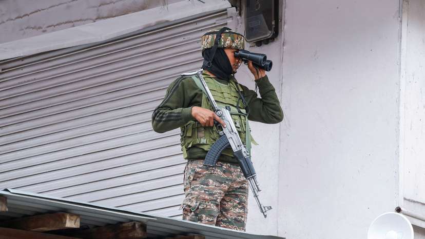An Indian security force personnel uses binoculars as he stands on a rooftop, following the Pahalgam attack in south Kashmir, in Srinagar