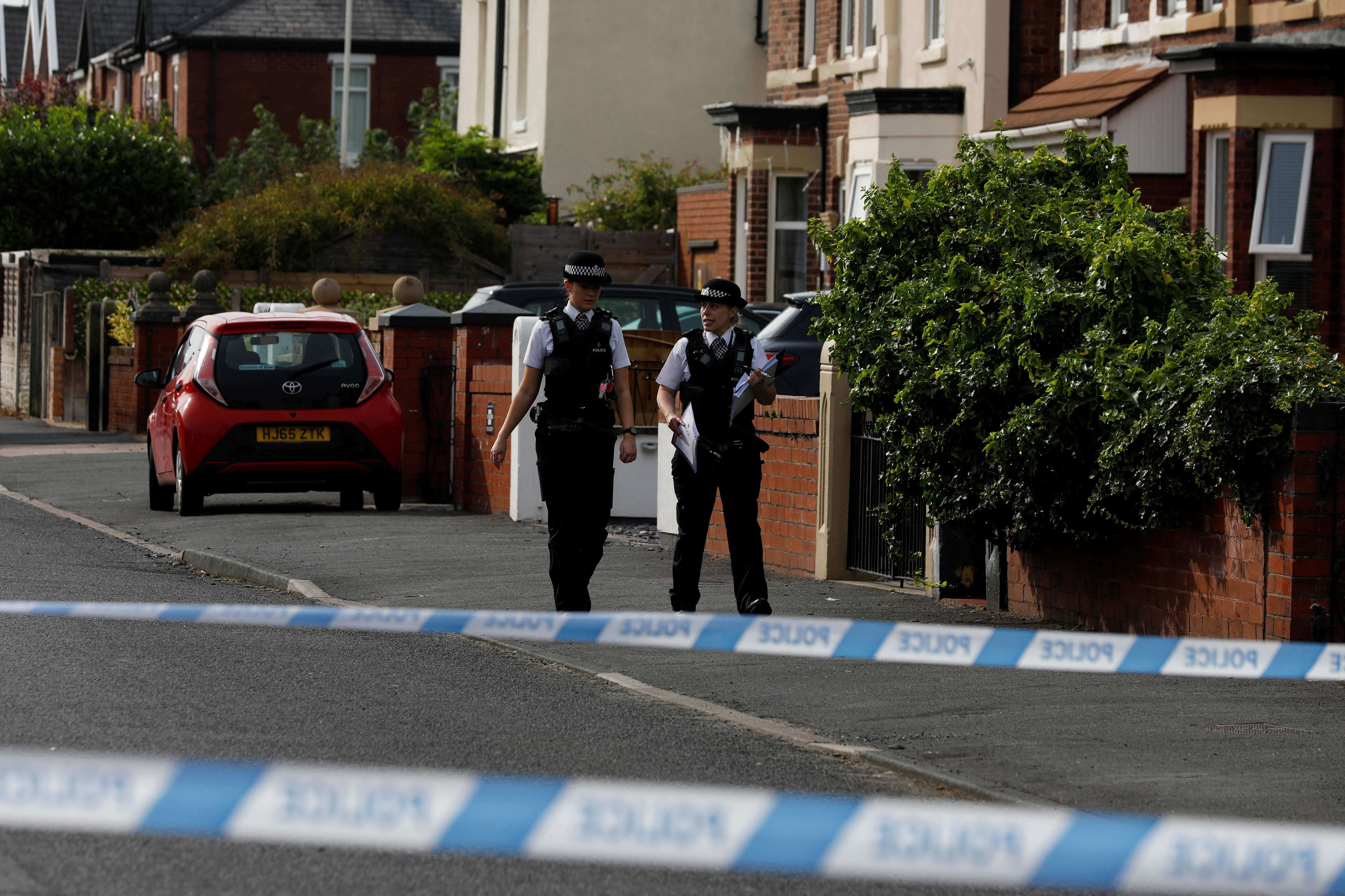 Police officers walk near the scene in Hart street where a man was arrested after people were stabbed in Southport