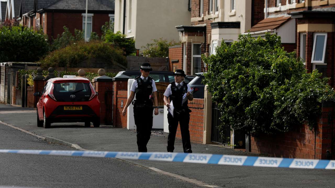Police officers walk near the scene in Hart street where a man was arrested after people were stabbed in Southport