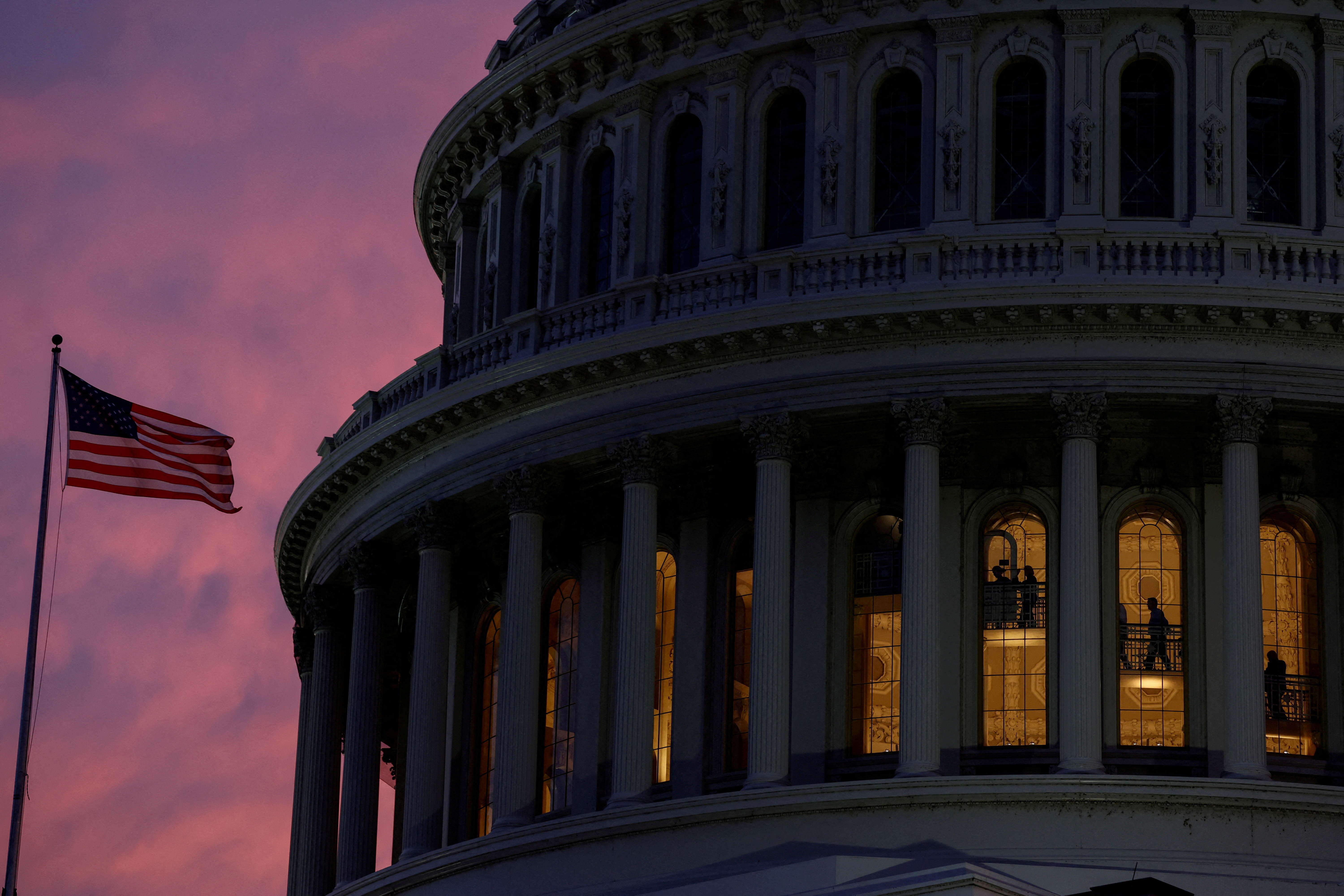 FILE PHOTO: People walk inside the upper floors of the rotunda of the U.S. Capitol building at sunset in Washington