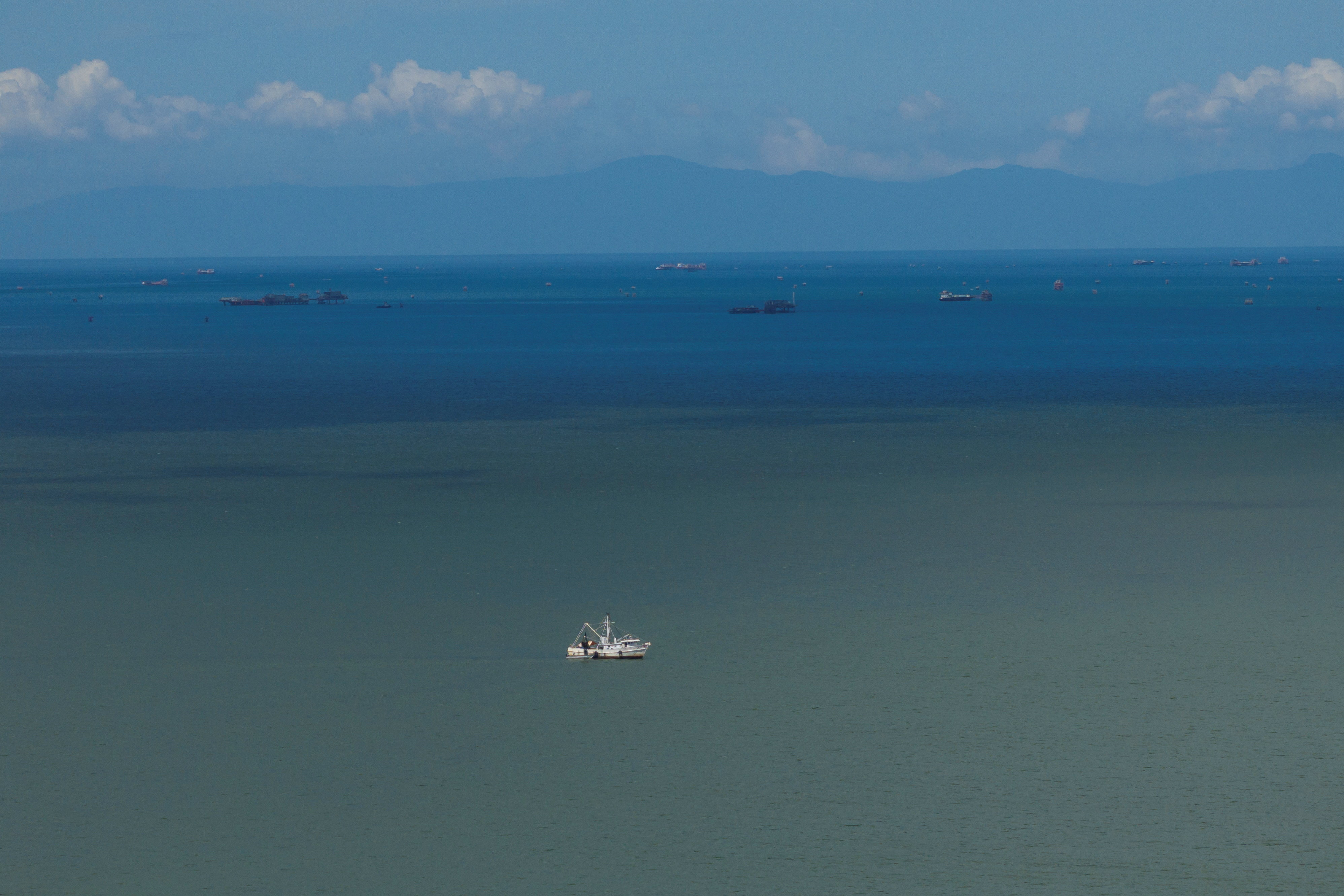A drone view of a fishing boat anchored in the Gulf of Paria, and the coast of Venezuela in the back, in Cedros
