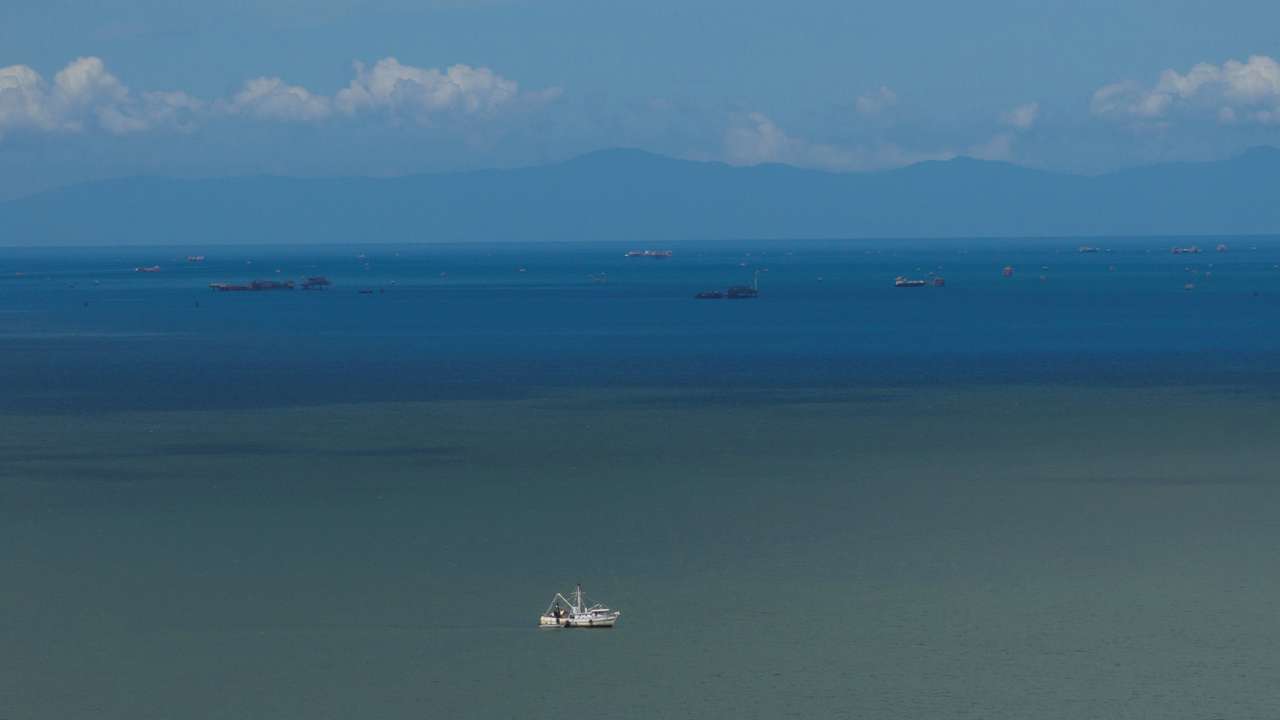 A drone view of a fishing boat anchored in the Gulf of Paria, and the coast of Venezuela in the back, in Cedros