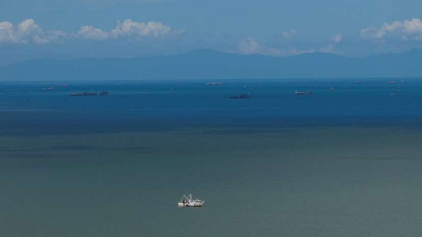 A drone view of a fishing boat anchored in the Gulf of Paria, and the coast of Venezuela in the back, in Cedros