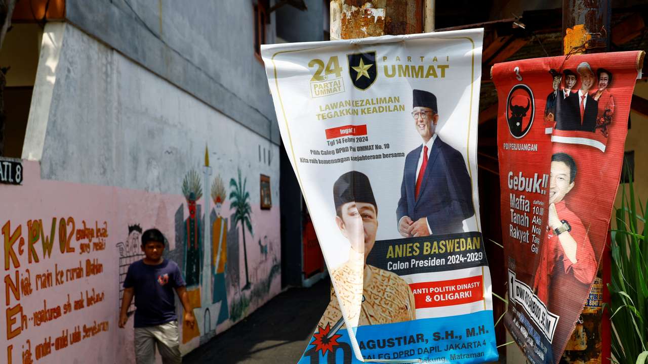 A boy walks past posters bearing the images of Presidential candidates Anies Baswedan and Ganjar Pranowo at a residential area in Jakarta