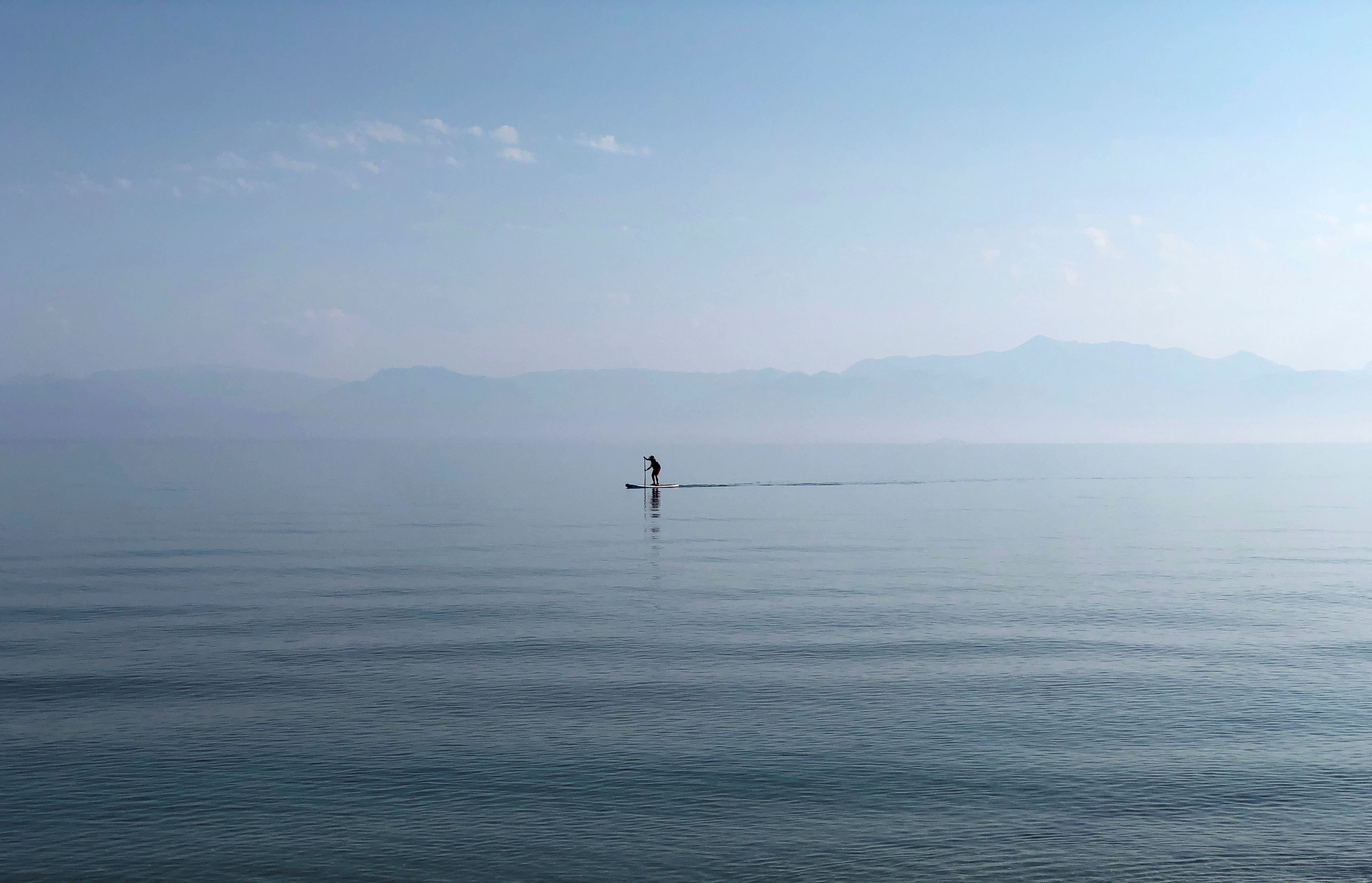 A man paddles in the Ionian Sea near the island of Corfu