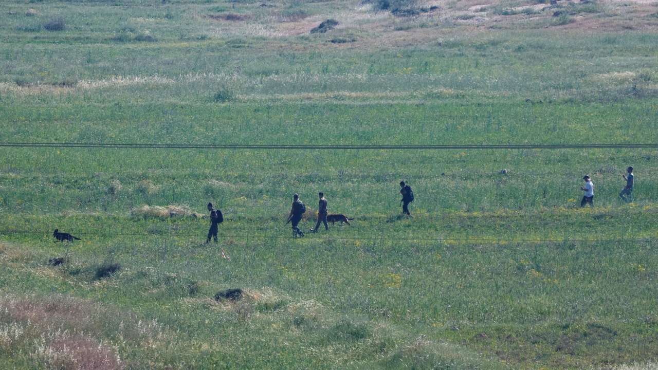 Israeli settlers look for a 14-year-old, who according to the Israeli military went missing in the area near the village of al-Mughayyer
