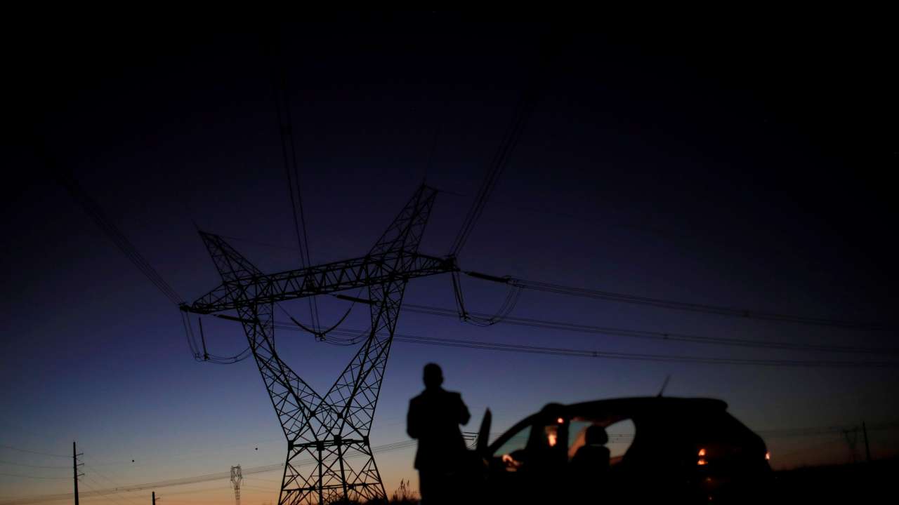 A man stands in front of power lines connecting pylons of high-tension electricity near Brasilia