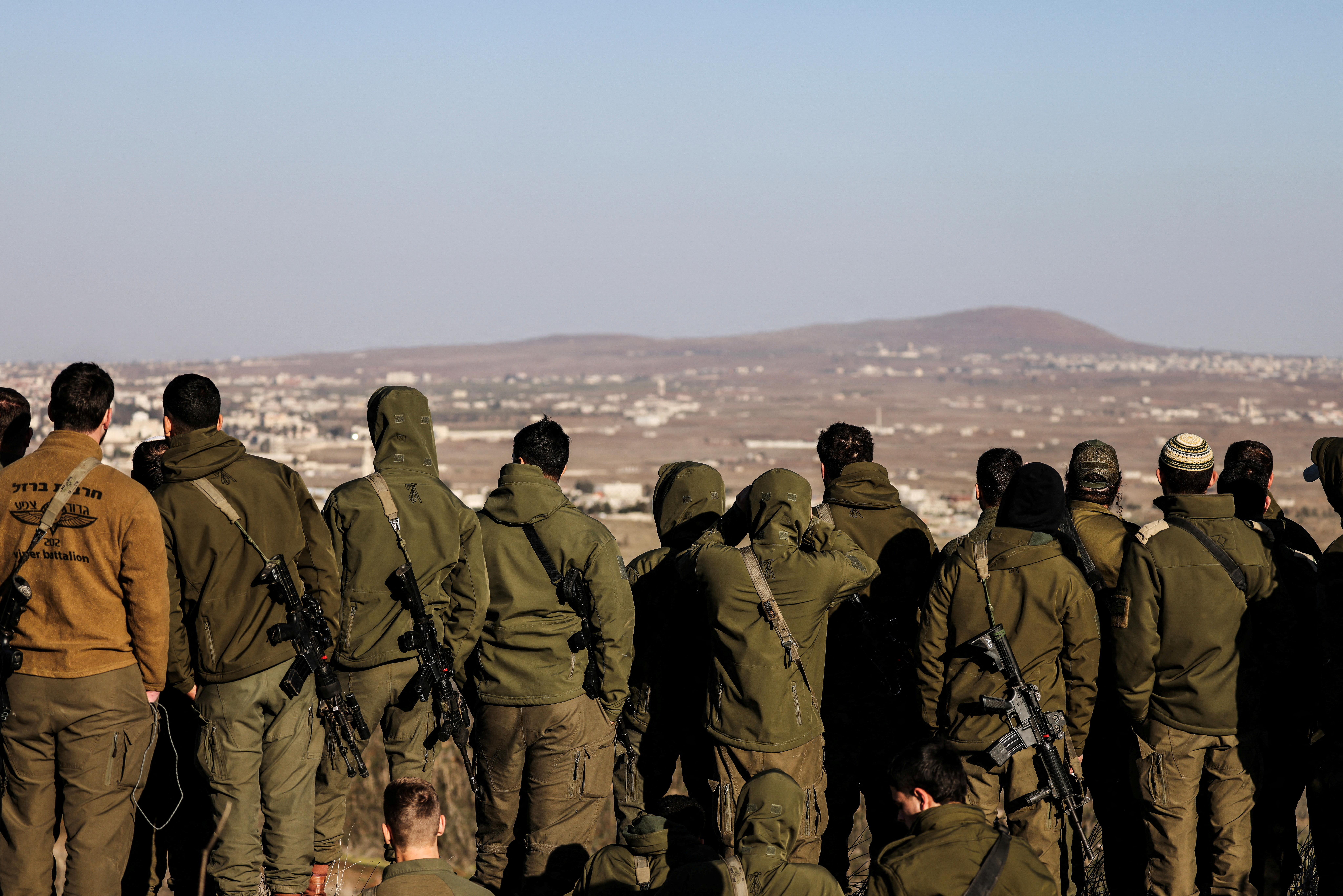 FILE PHOTO: Israeli soldiers look into Syria, after the ousting of Syria's Bashar al-Assad, in Ein Zivan in the Israeli-occupied Golan Heights
