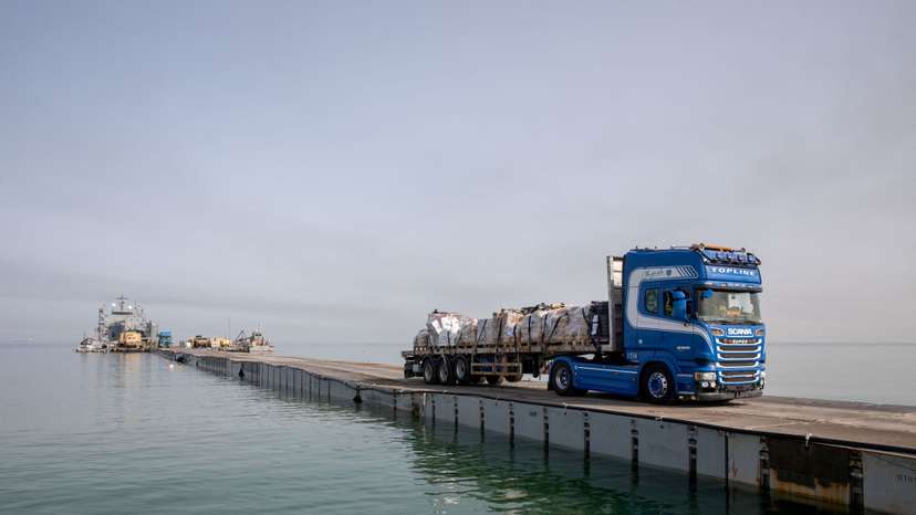 Trucks deliver humanitarian aid over a temporary pier on the Gaza coast