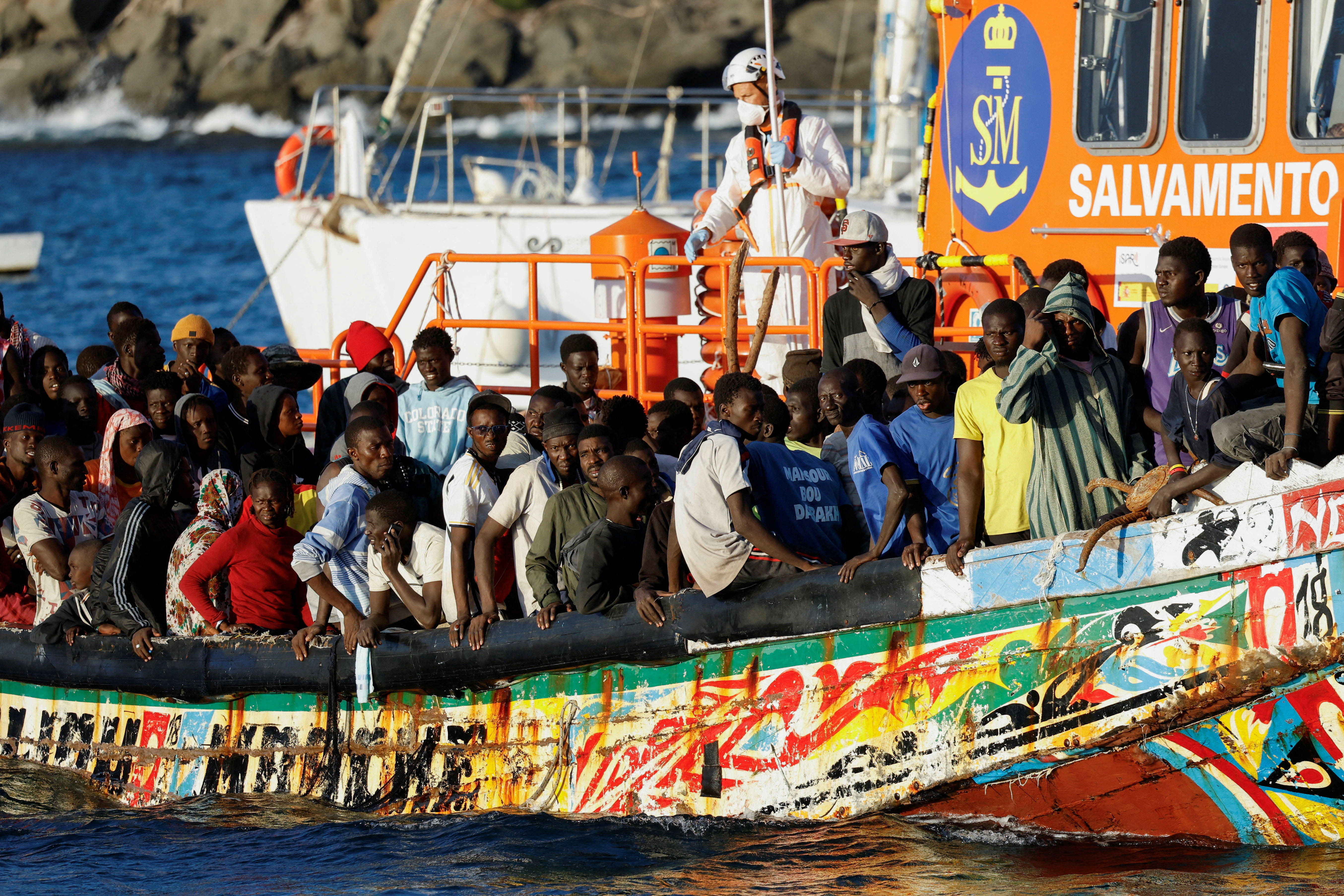 FILE PHOTO: Group of migrants in a wooden boat are towed by a Spanish coast guard vessel to the port of Arguineguin