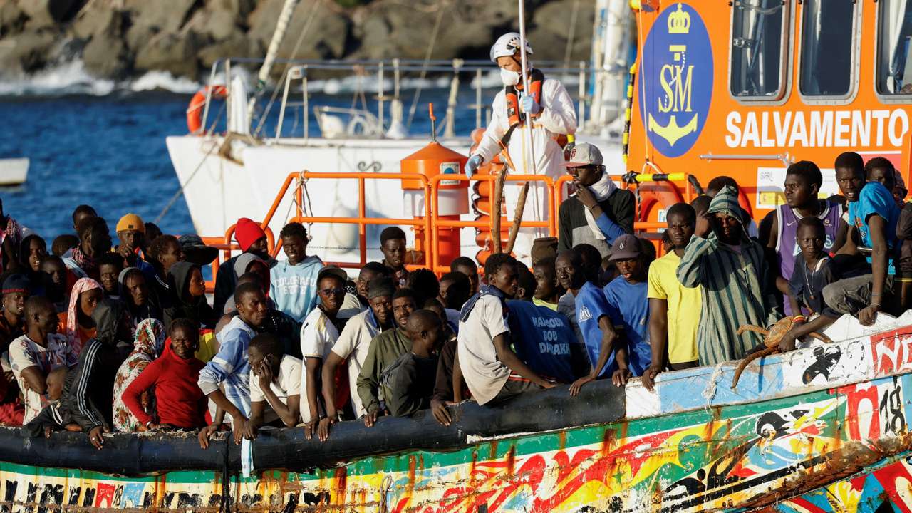 FILE PHOTO: Group of migrants in a wooden boat are towed by a Spanish coast guard vessel to the port of Arguineguin