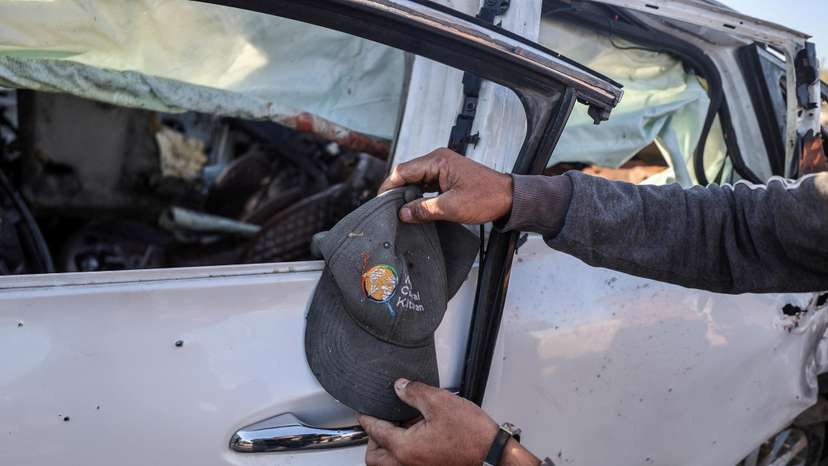 A person holds a cap next to a vehicle in which employees of the World Central Kitchen (WCK) were killed in an Israeli strike