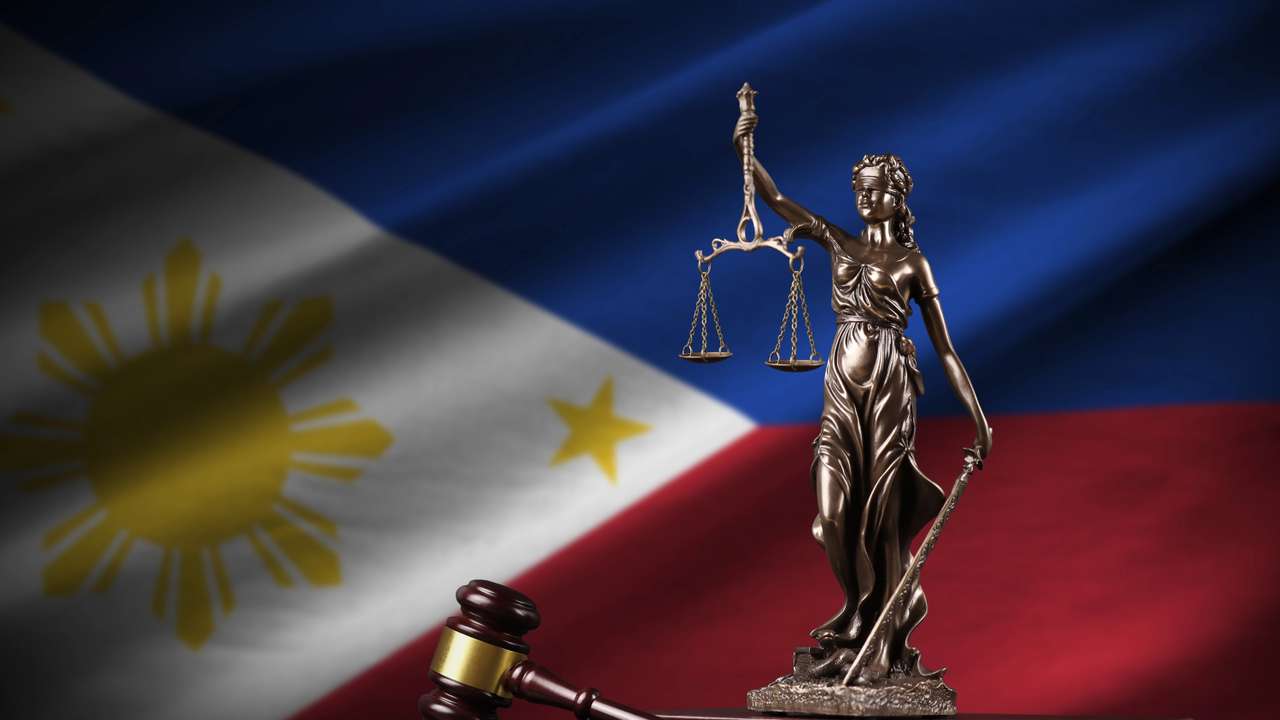 Philippines flag with statue of lady justice, constitution and judge hammer on black drapery. Concept of judgement and punishment