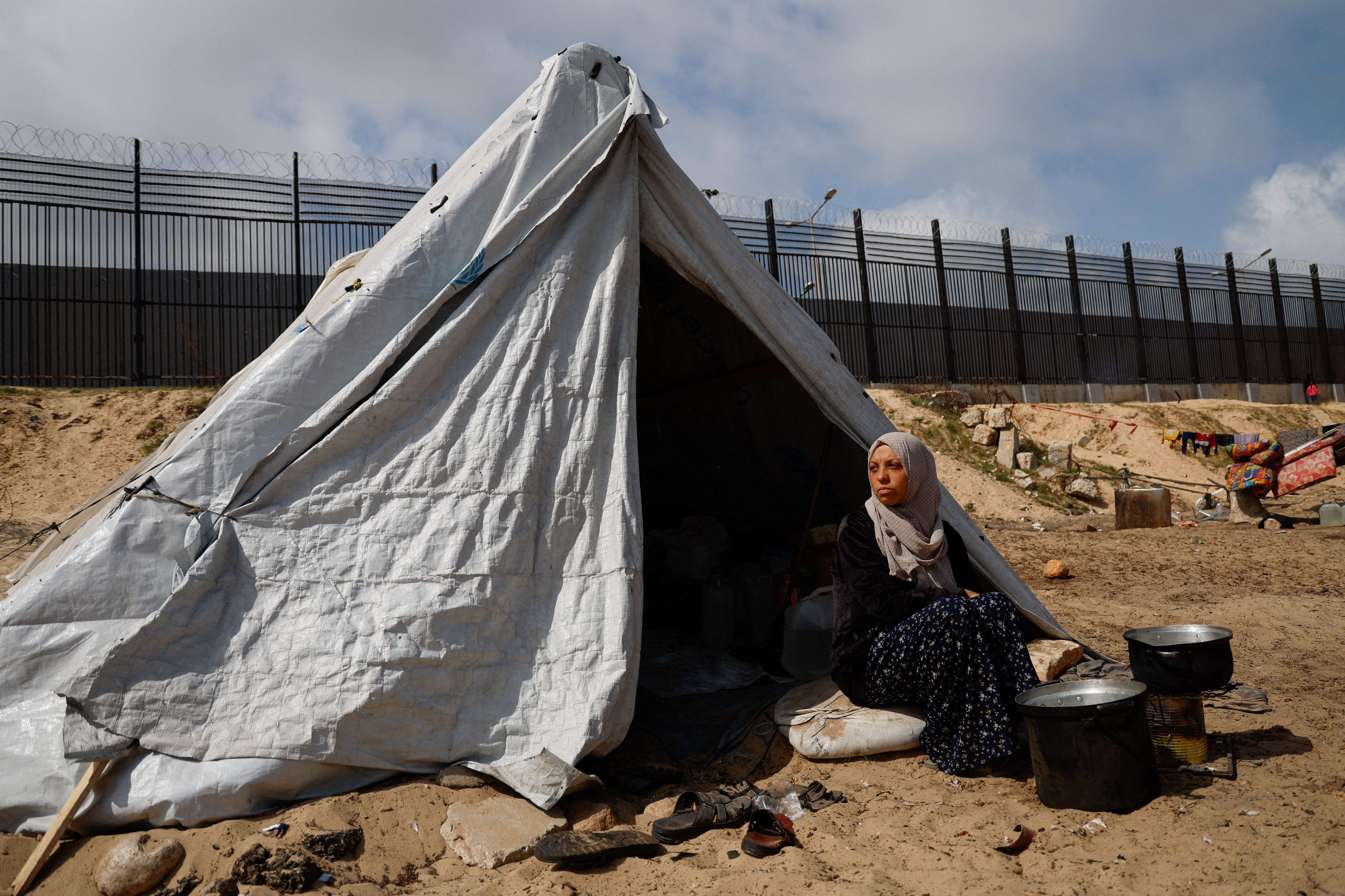 Displaced Palestinian women, who fled their houses due to Israeli strikes shelter in a tent camp, in Rafah
