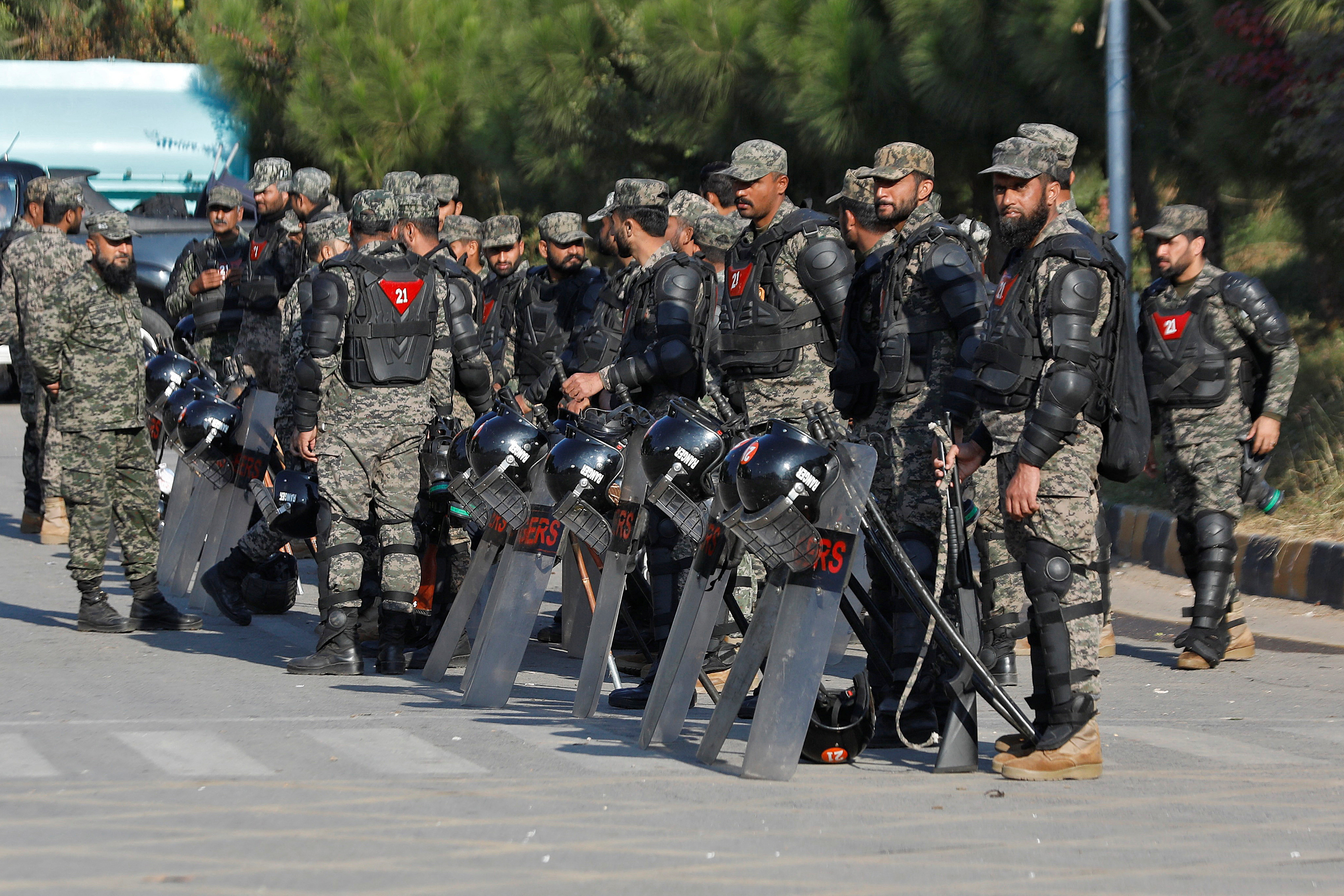 Pakistani Rangers in riot gear stand guard alongside a road to prevent an anti-government rally, in Islamabad