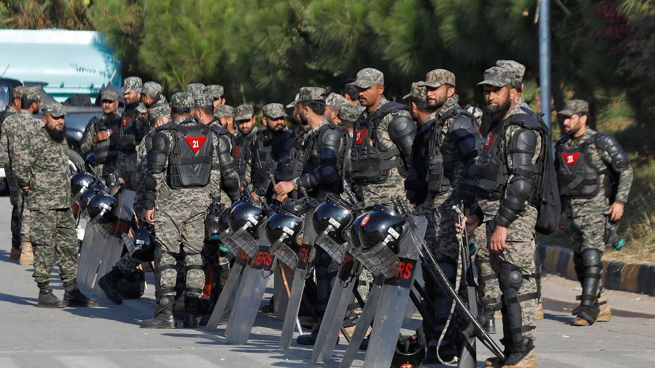 Pakistani Rangers in riot gear stand guard alongside a road to prevent an anti-government rally, in Islamabad