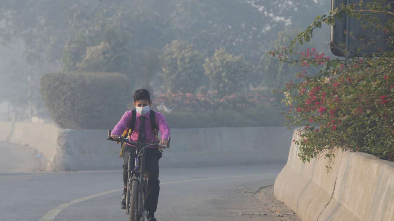 FILE PHOTO: Student rides a bicycle to school amid dense smog in Lahore