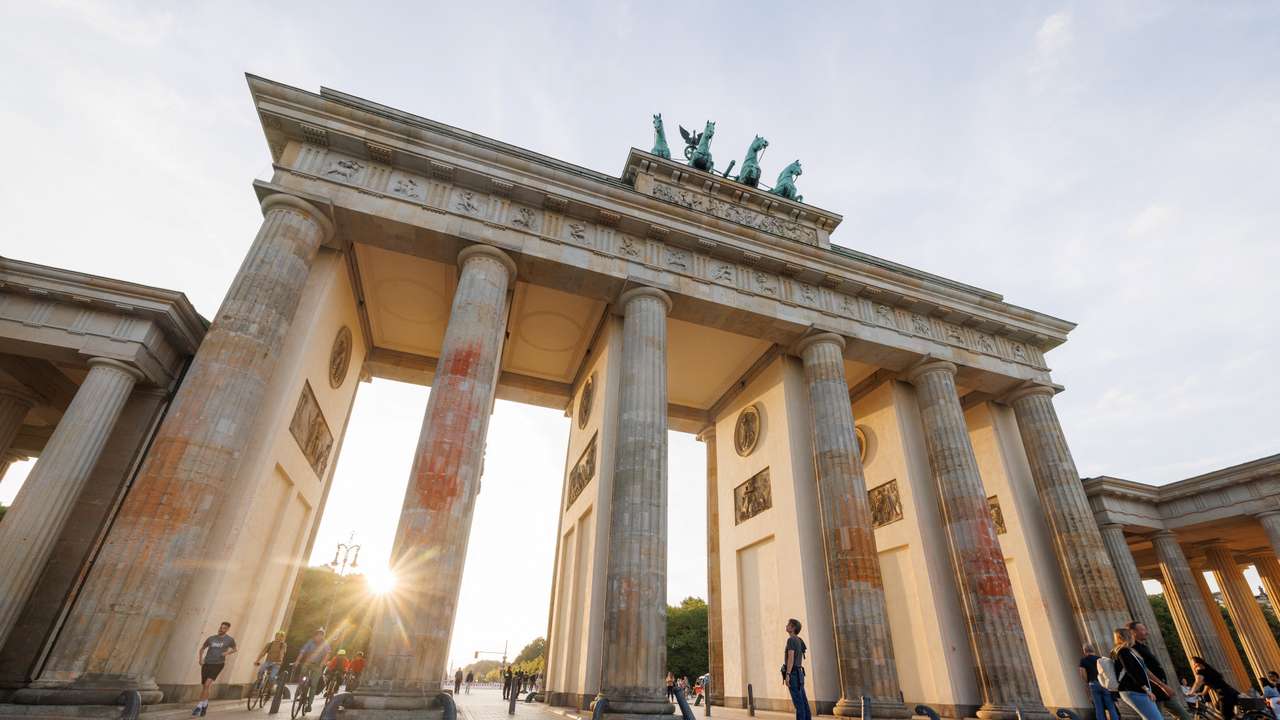 The sun sets behind Brandenburg Gate and its columns that were painted in a protest campaign by Last Generation climate activists in Berlin