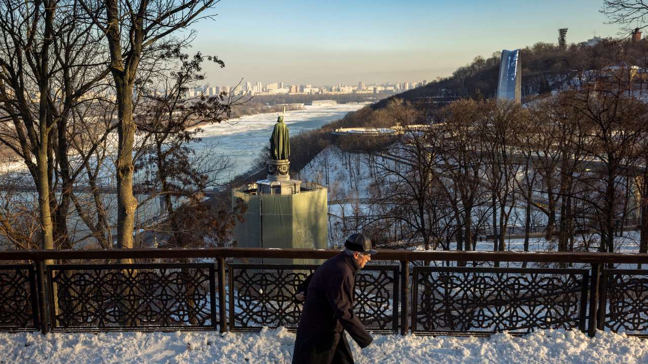 A man walks in a park overlooking Dnipro River on a sunny winter day in Kyiv