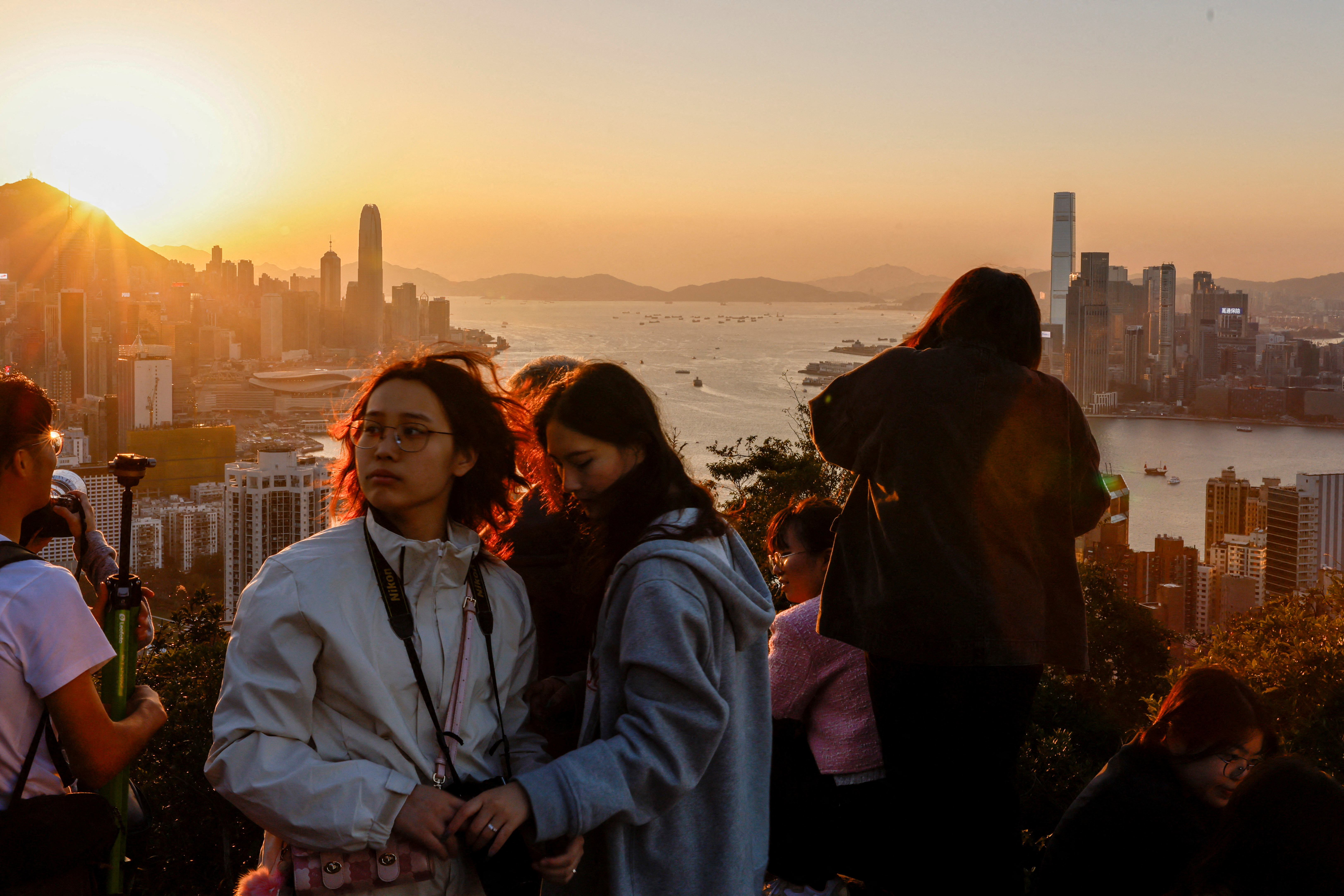 FILE PHOTO: People watch the sunset over Victoria Harbour from a mountaintop in Hong Kong