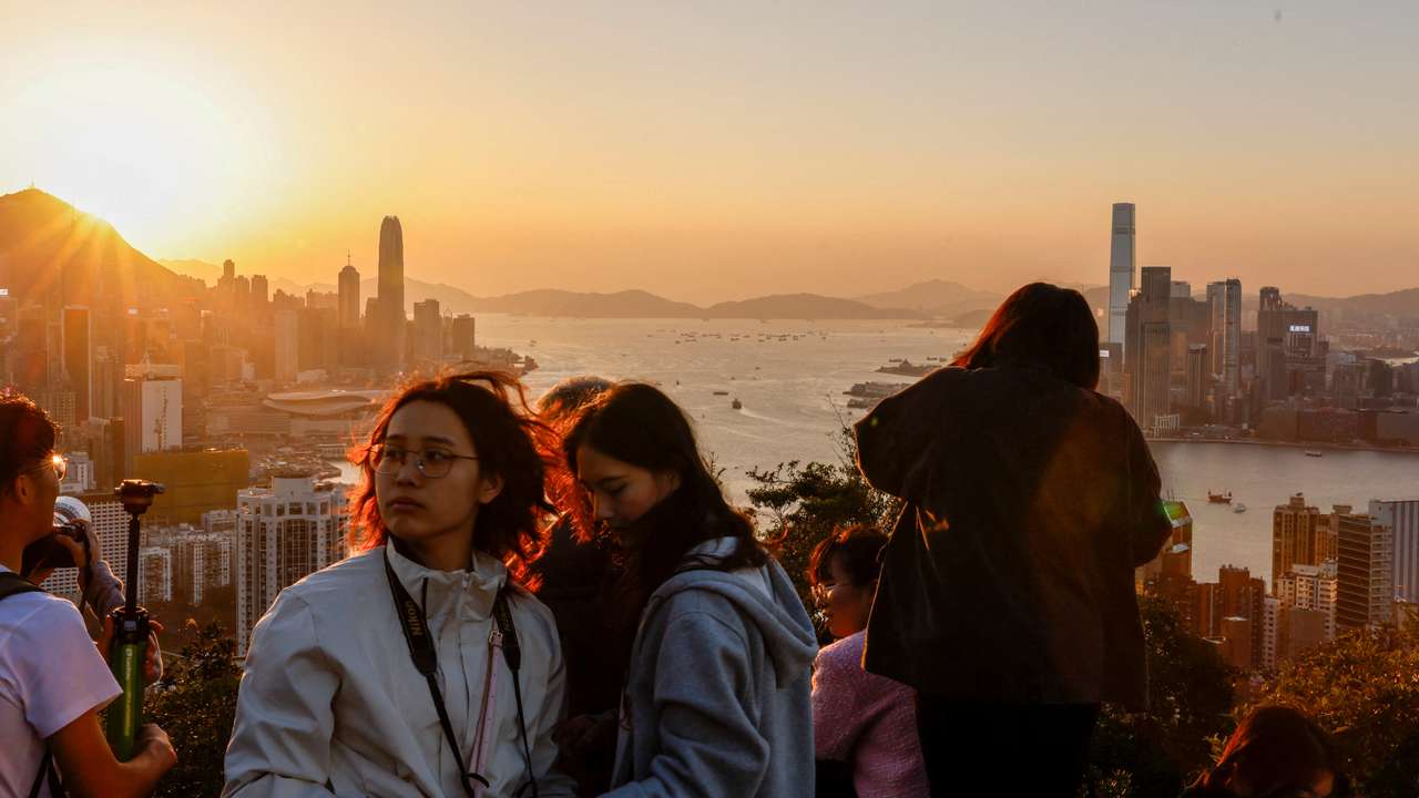 FILE PHOTO: People watch the sunset over Victoria Harbour from a mountaintop in Hong Kong