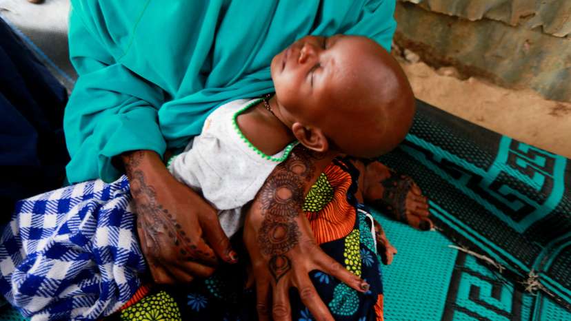 FILE PHOTO: A mother carries her sleeping baby during a safety training workshop for displaced Boko Haram victims on the identification of dangerous objects, at the Gubio camp in Maiduguri