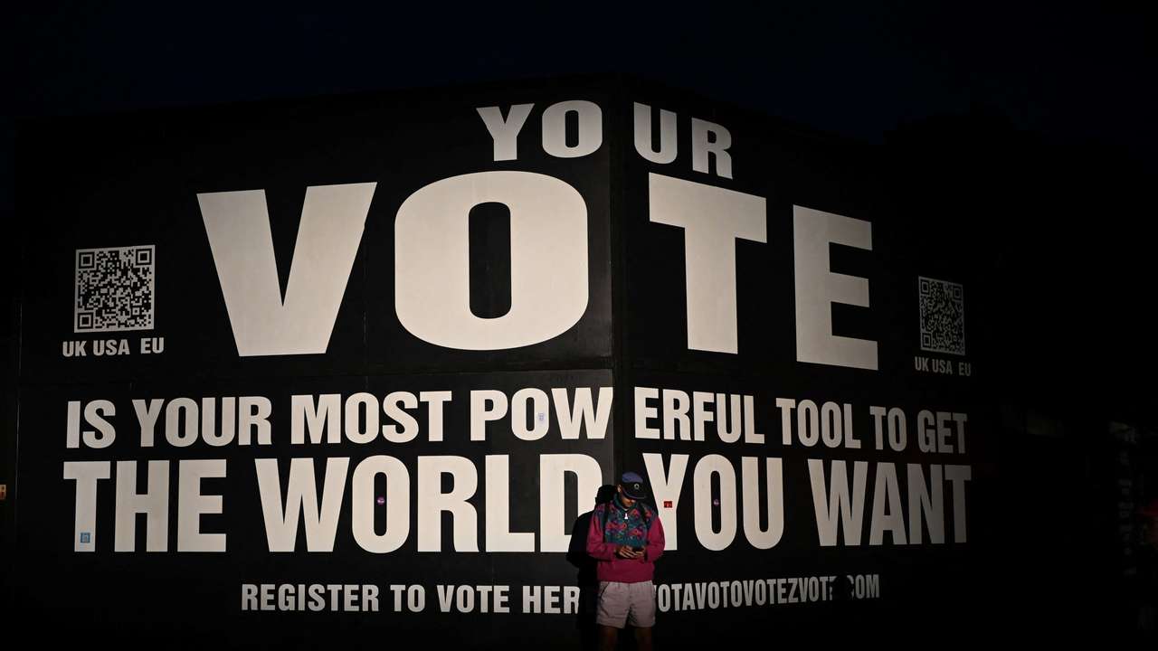 A reveller stands in front of a banner urging people to vote, at Worthy Farm in Somerset during the Glastonbury Festival