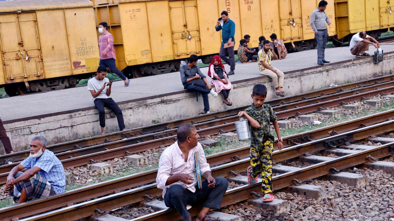 Commuters sit on railway tracks as they wait at Tejgaon Railway Station in Dhaka