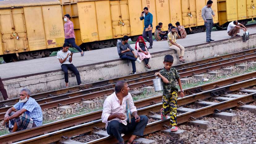 Commuters sit on railway tracks as they wait at Tejgaon Railway Station in Dhaka