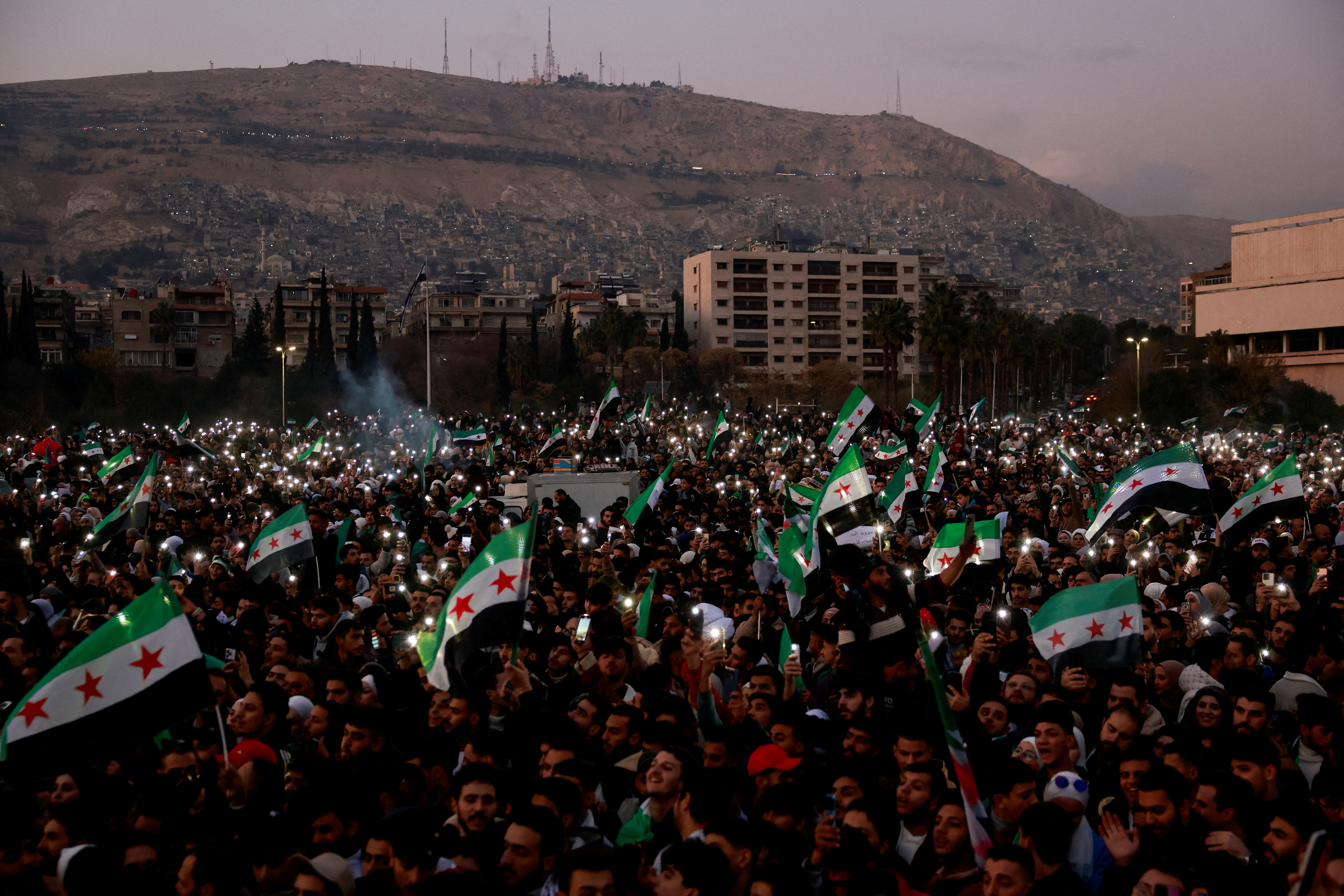 People gather during a celebration called by Hayat Tahrir al-Sham (HTS) after the ousting of Syria's Bashar al-Assad, in Damascus