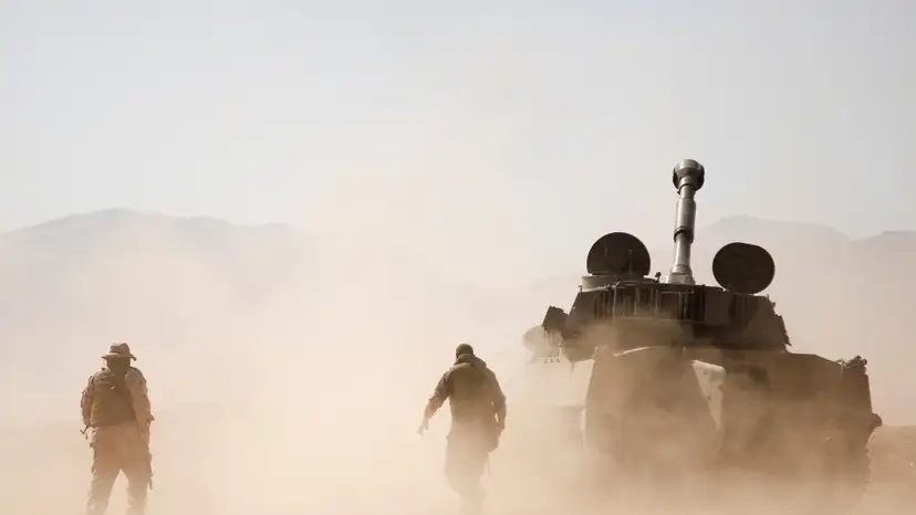 Hezbollah fighter walk near a military tank in Western Qalamoun