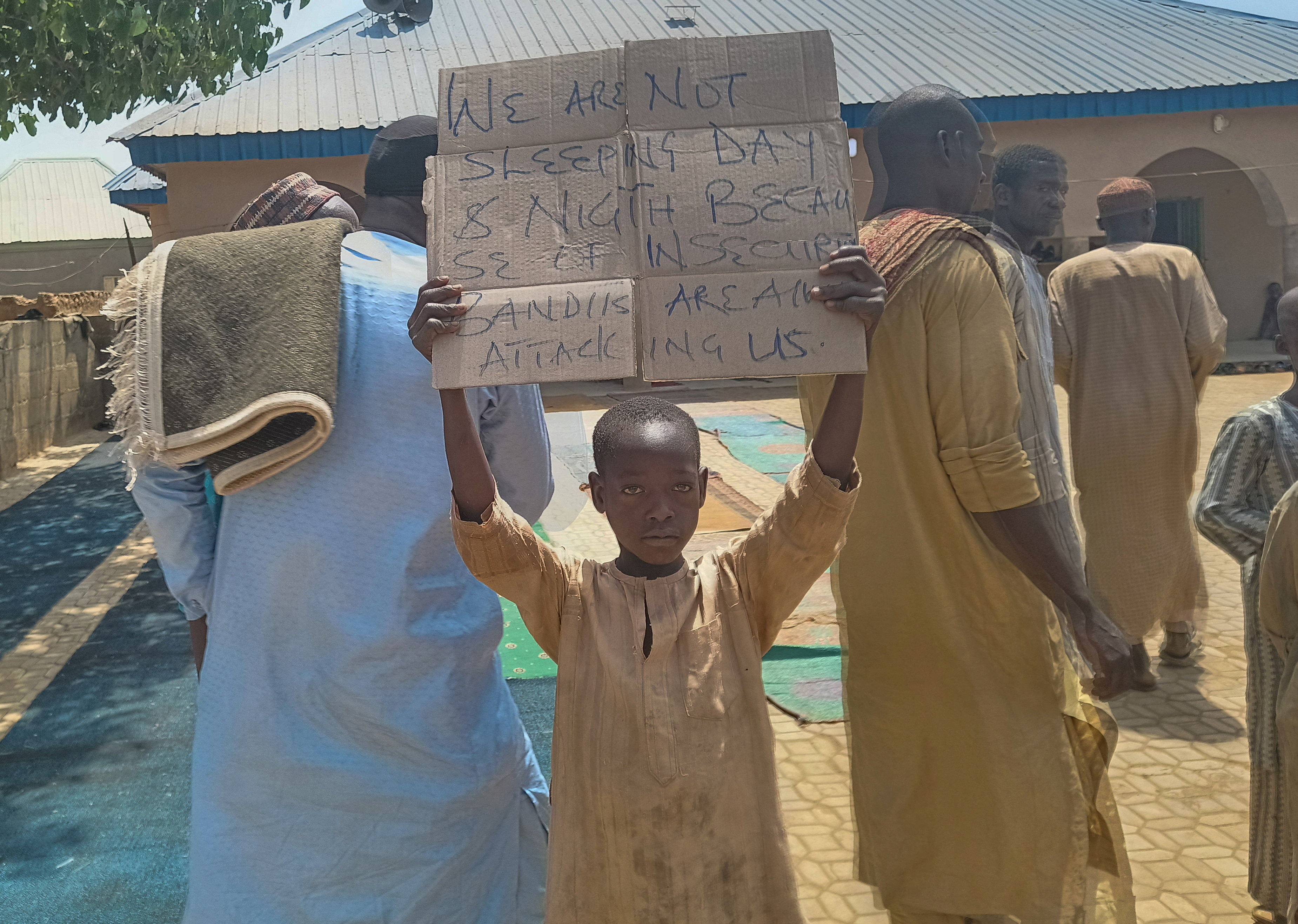 A boy holds a sign to protest against, what a teacher, local councilor and parents said, the kidnapping of hundreds school pupils by gunmen after the Friday prayer, in Kaduna
