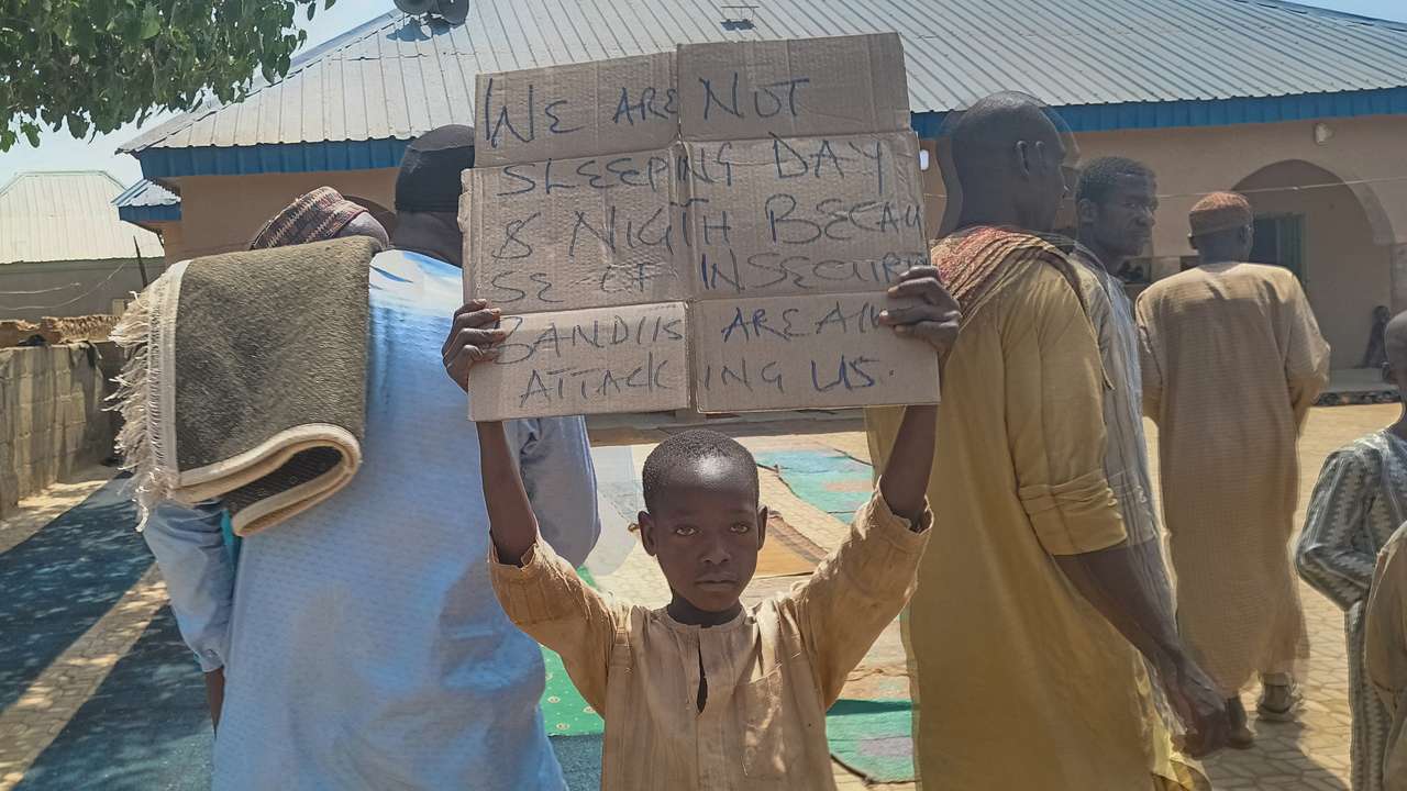 A boy holds a sign to protest against, what a teacher, local councilor and parents said, the kidnapping of hundreds school pupils by gunmen after the Friday prayer, in Kaduna